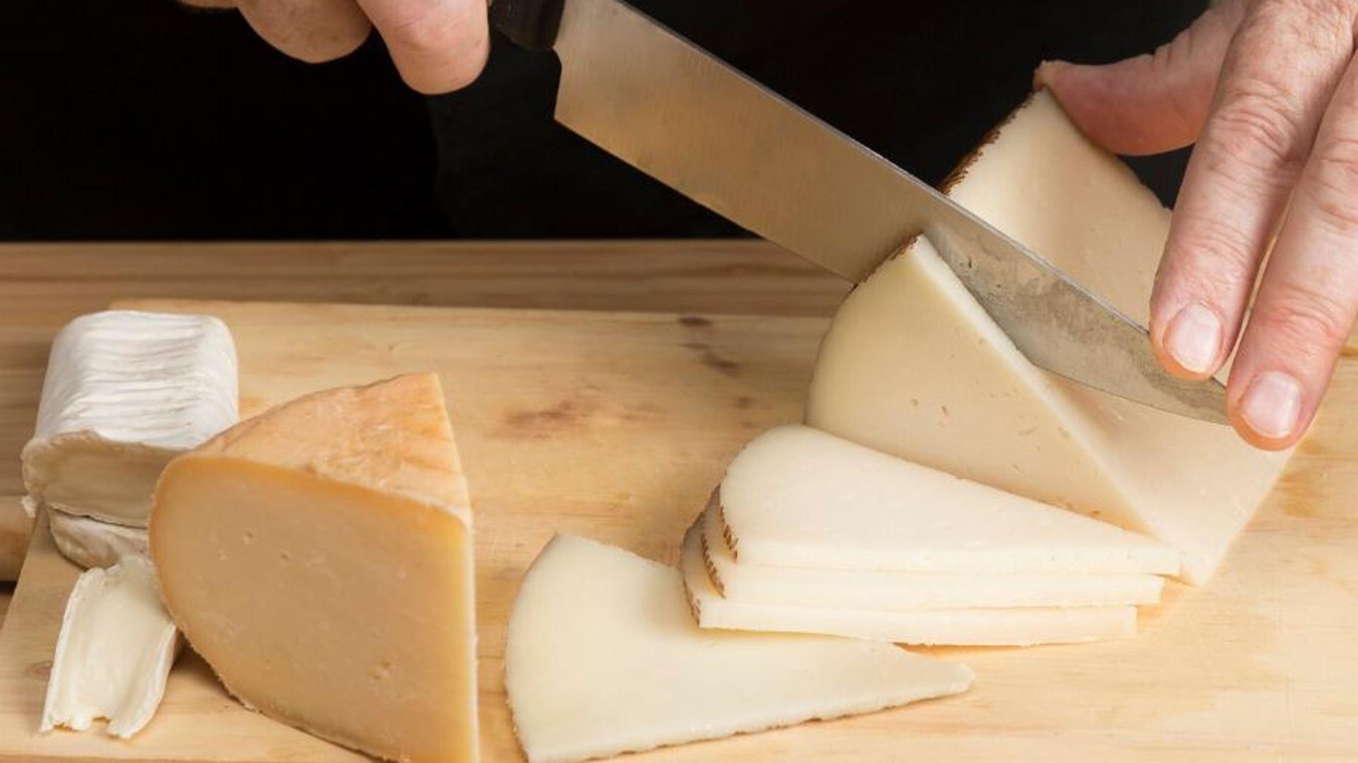 Imagen de archivo de una persona cortando queso