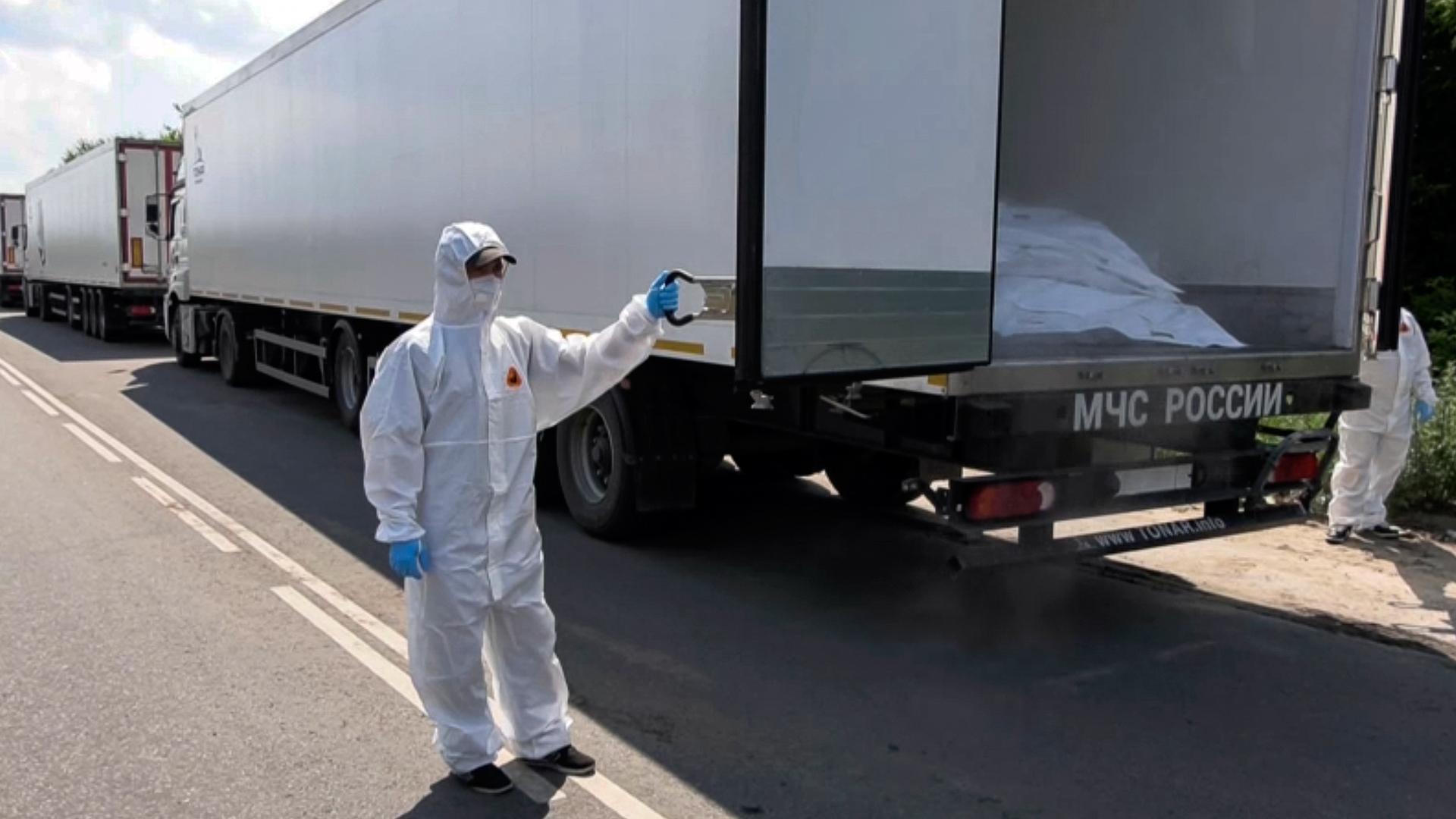 Un oficial con traje de protección contra materiales peligrosos abriendo un camión, parte de un convoy con 1.212 cadáveres de militares ucranianos fallecidos para ser repatriados