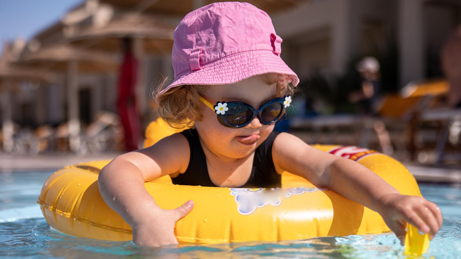 Una niña con gafas de sol en la piscina