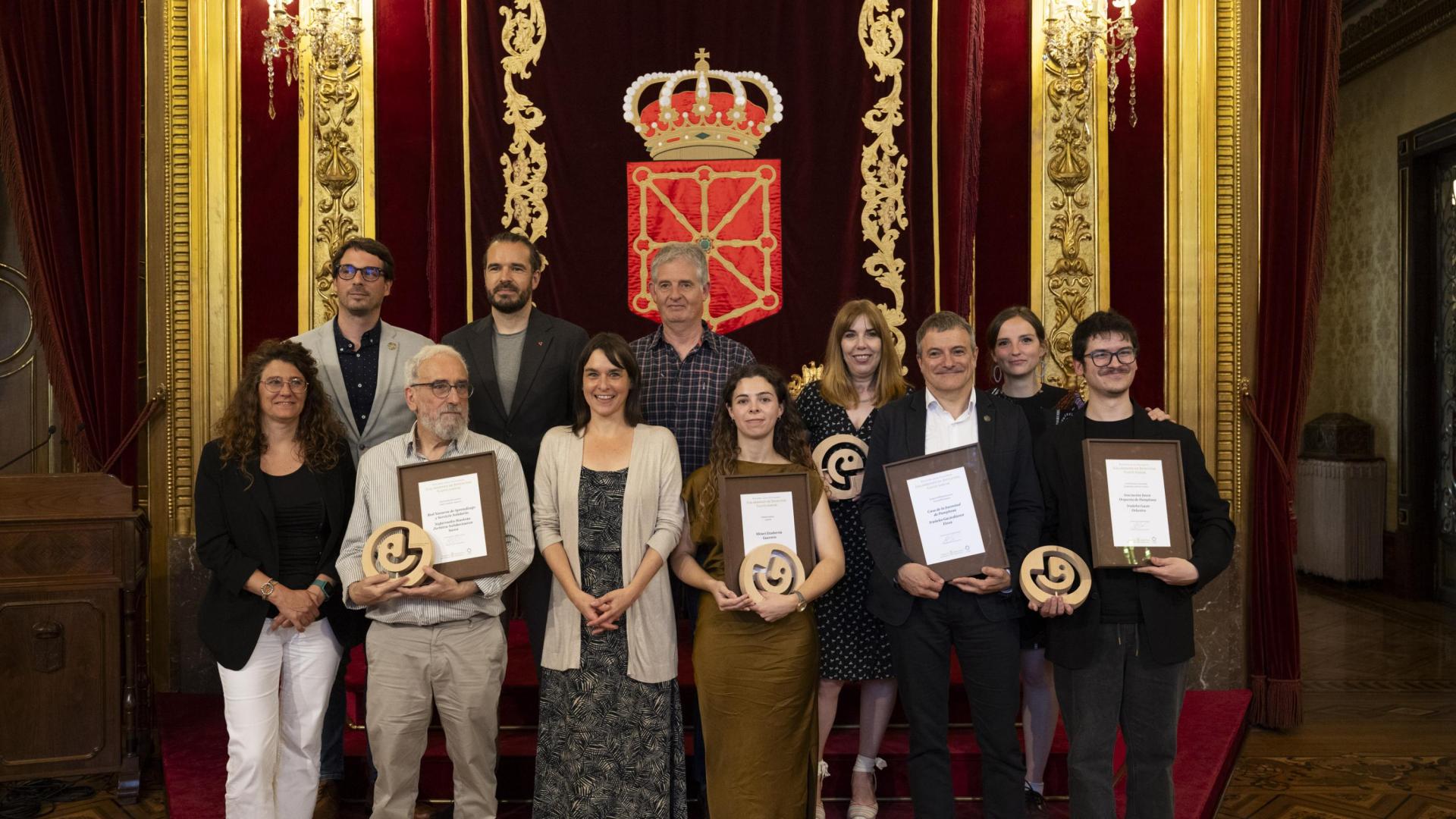 Los premiados, con diplomas, posan junto a autoridades y amigos en el Palacio de Navarra.