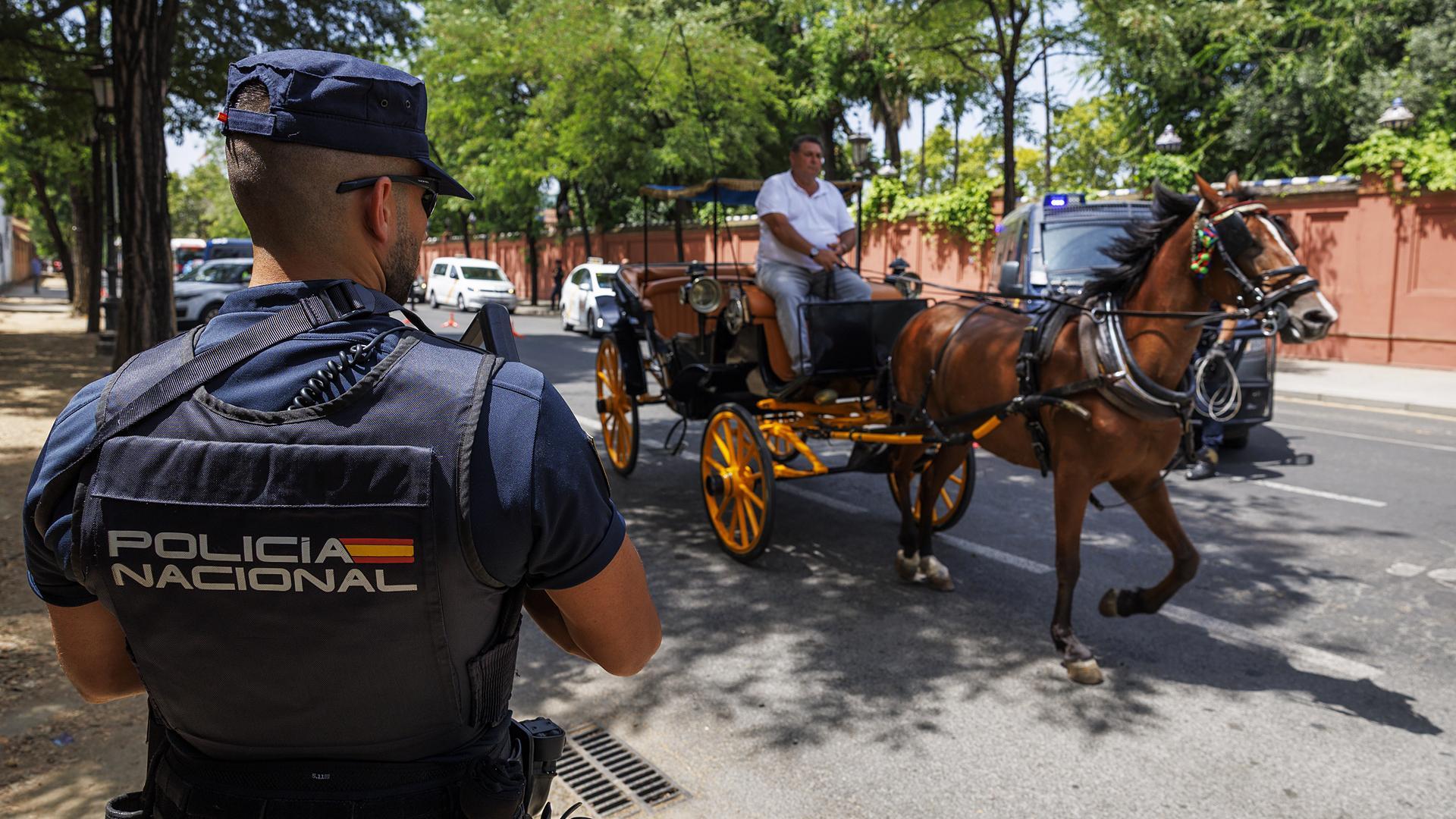 Un agente de la Policía Nacional observa el paso de un coche de caballos en una calle de Sevilla en el operativo de seguridad ante al cumbre de la ONU /