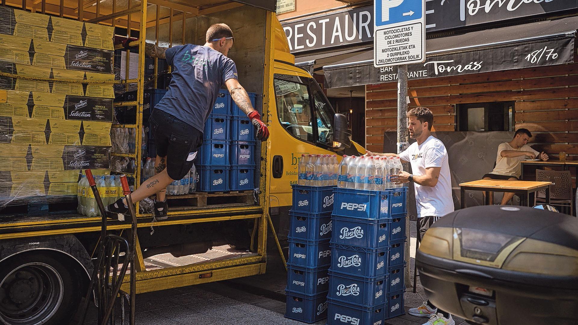Trabajadores descargan los pedidos de última hora en los locales del centro de Pamplona.