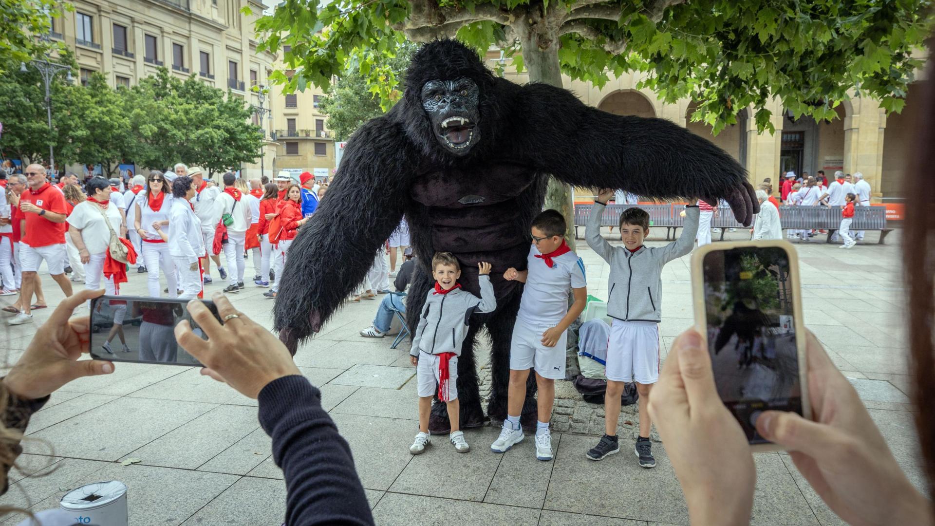 Un orangután de grandes dimensiones posa junto a tres niños que le hacen cosquillas el sábado por la mañana en Pamplona.