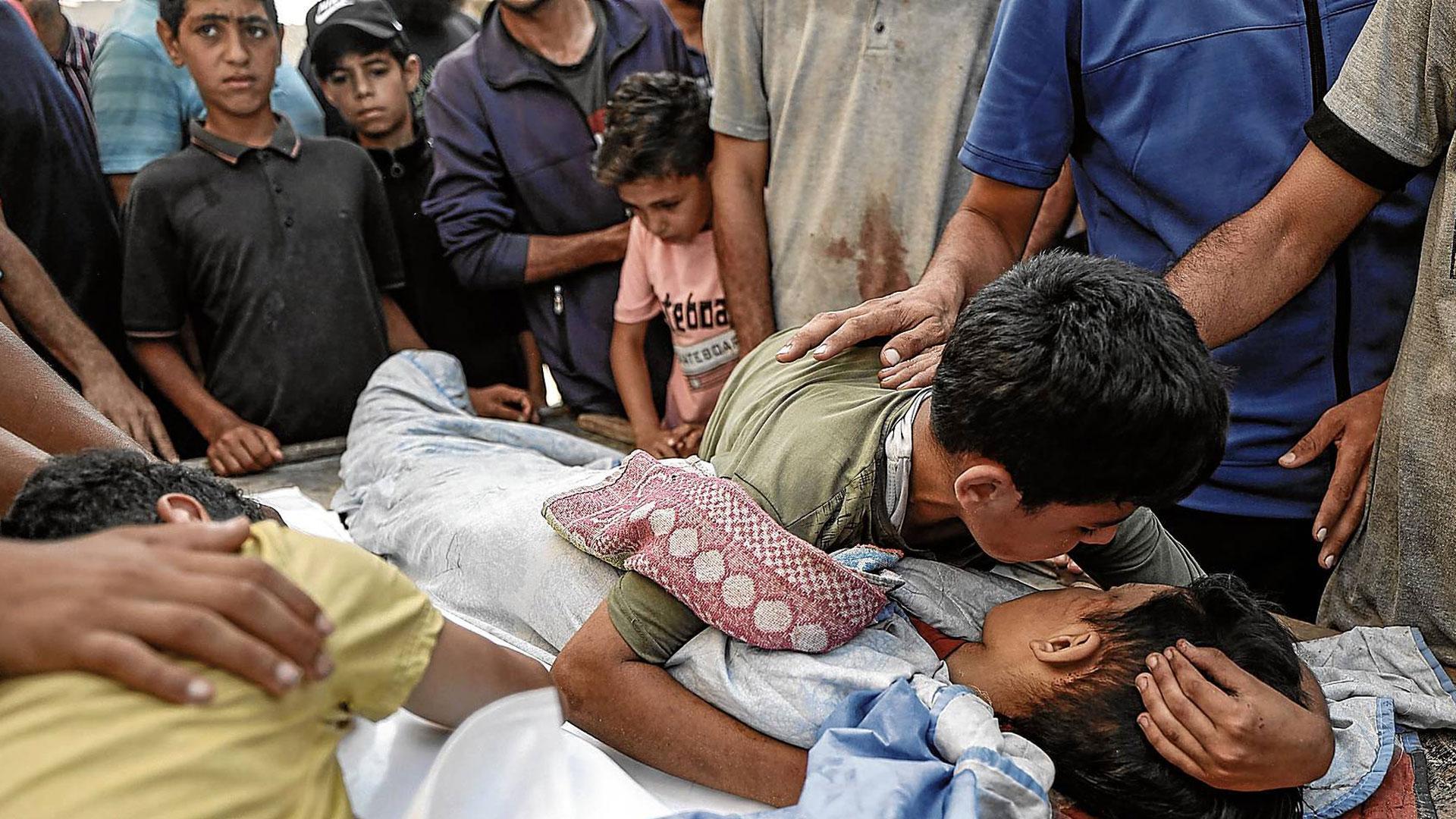 Un niño palestino se despide de su hermano fallecido en el bombardeo israelí contra el punto de distribución de agua en Nuseirat