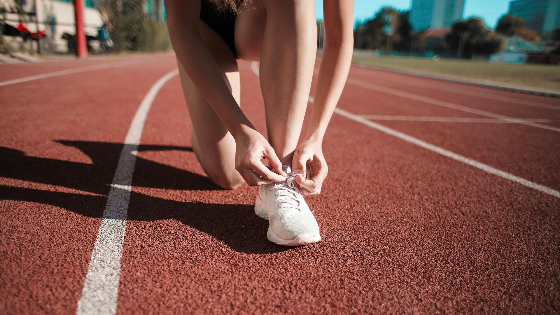 Un atleta se ata las zapatillas sobre el tartán /