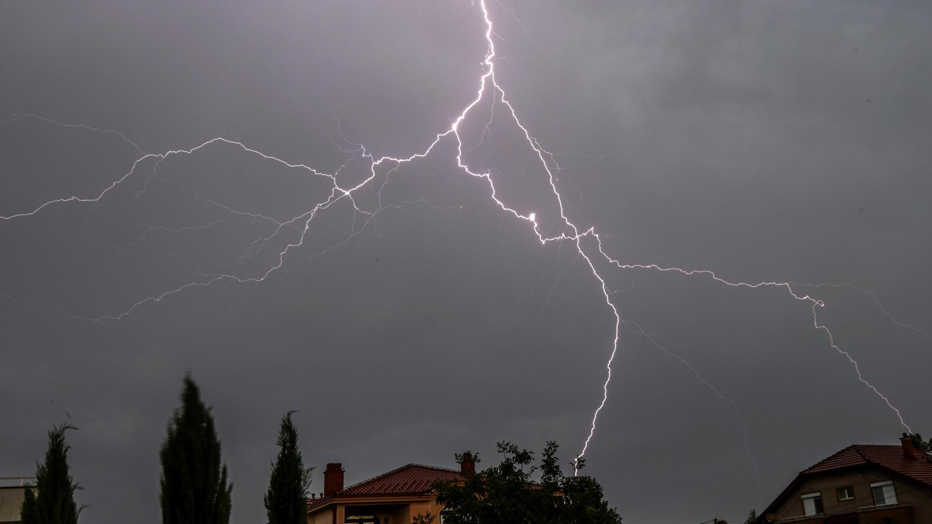 Un rayo que cae cerca de unas casas en una tormenta eléctrica