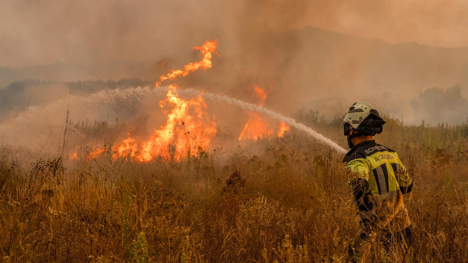 Un bombero trabaja en las labores de extinción del incendio forestal que permanece activo este martes en Monterrei (Ourense)