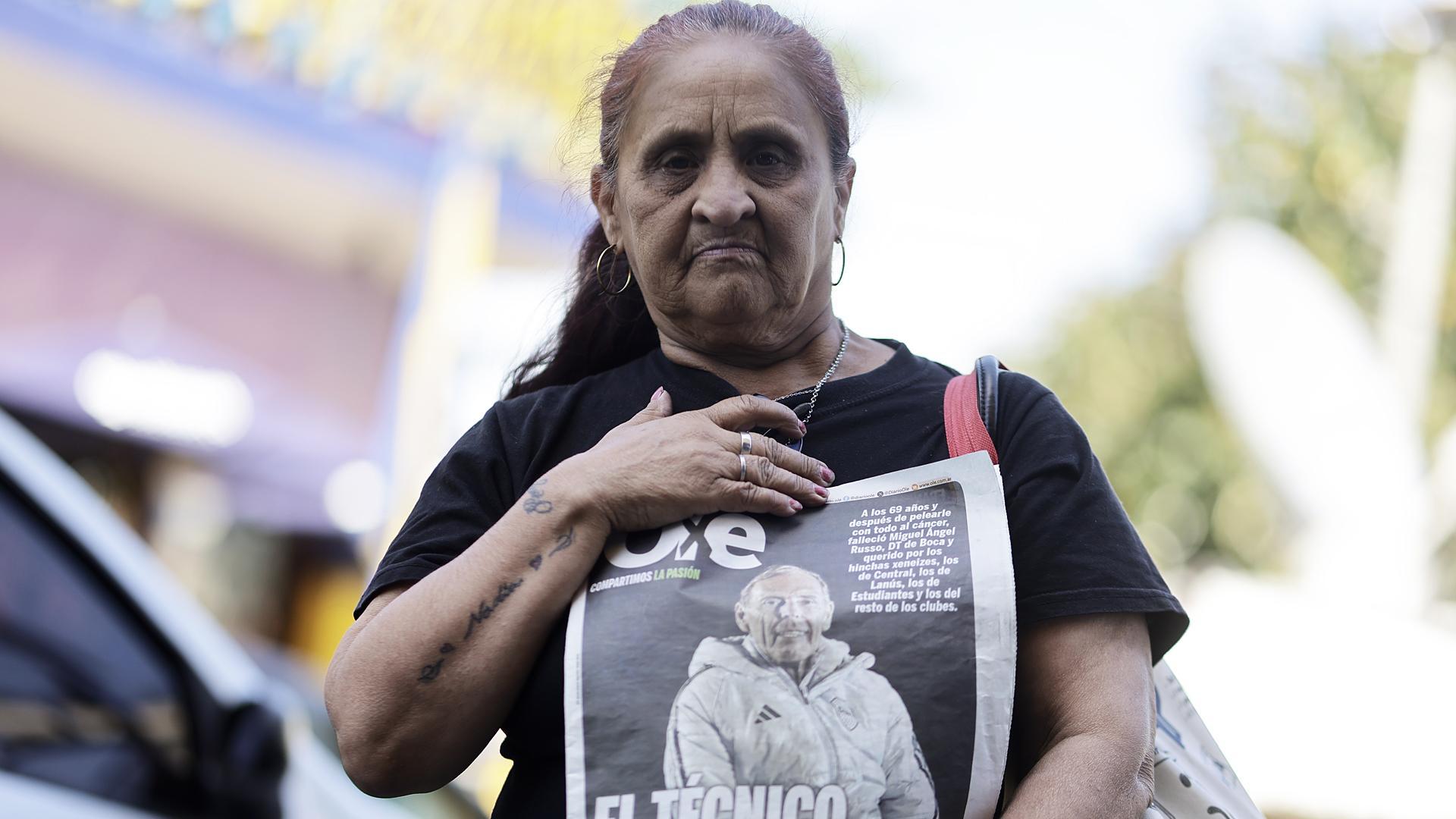 Una mujer sostiene un ejemplar de prensa con la noticia del fallecimiento del técnico de Boca Juniors Miguel Ángel Russo /