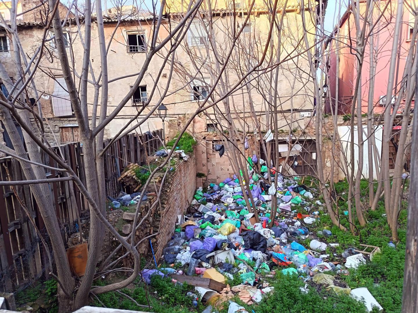 Imagen de las bolsas de basura y demás restos acumulados en el interior del solar situado entre las calles Cortes y Magallón de Tudela