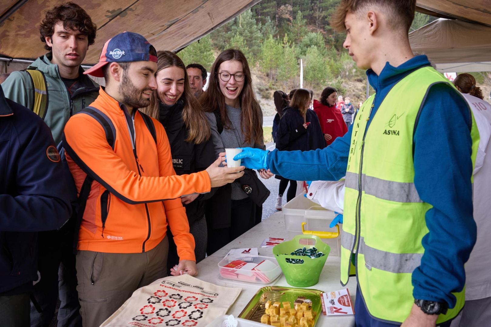 Peregrinos recibiendo comida y bebida en el puesto de avituallamiento gratuito de ASVONA.