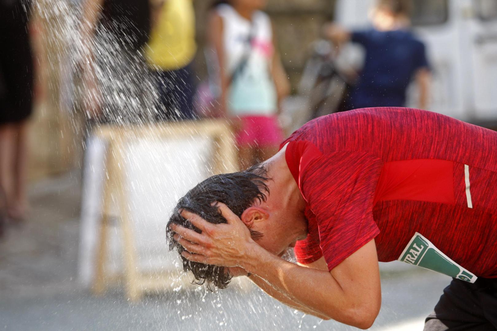 Un corredor, refrescándose durante una carrera popular en verano