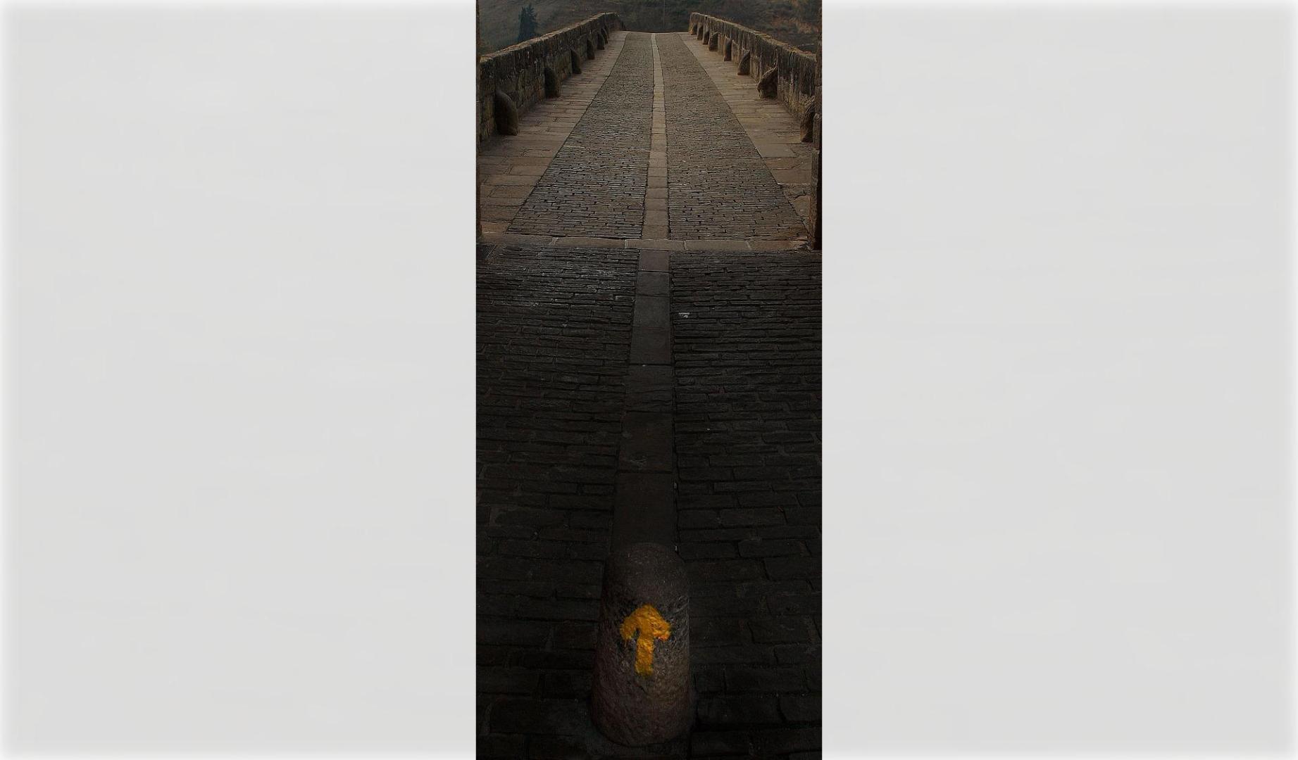 Una flecha amarilla señalizando el Camino de Santiago en Puente la Reina