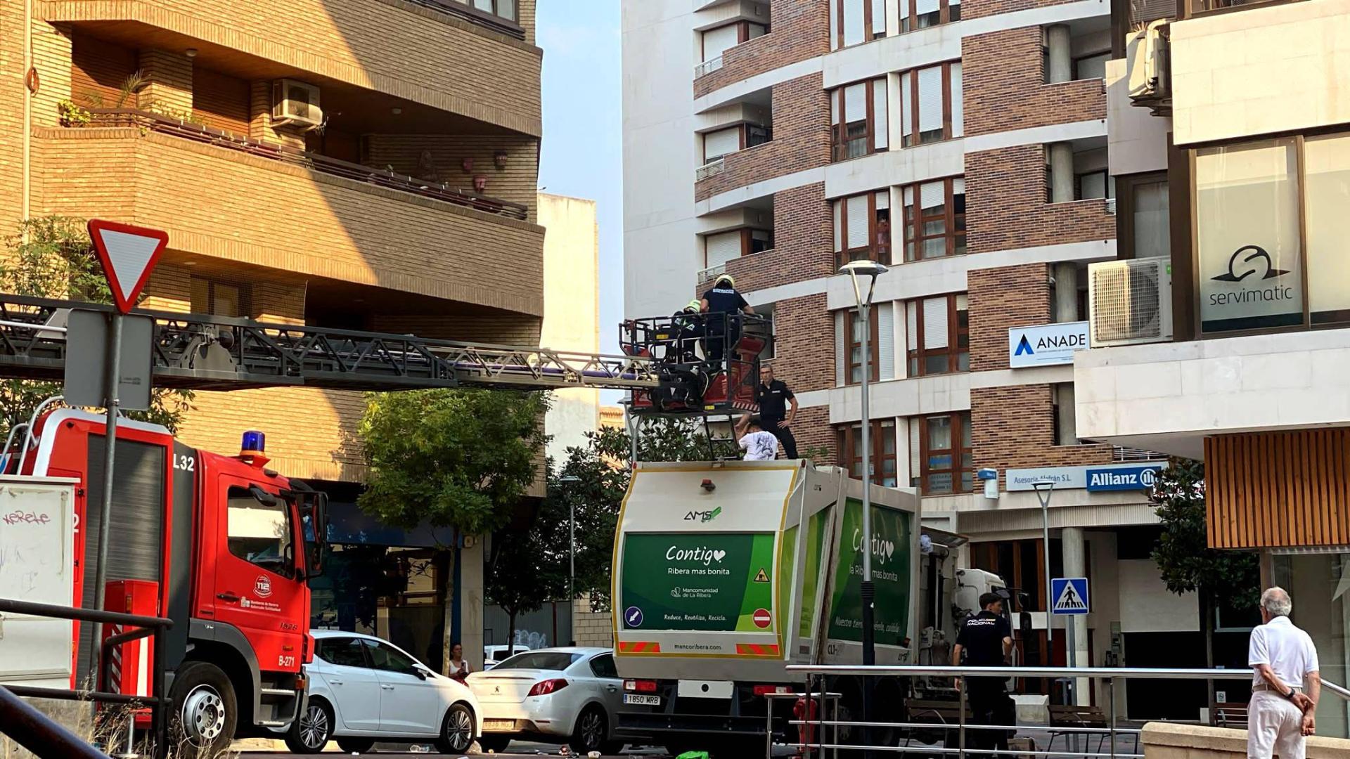Instante de la actuación de los bomberos y de la Policía Nacional para bajar al mozo que se había subido a lo alto del camión de recogida de basura