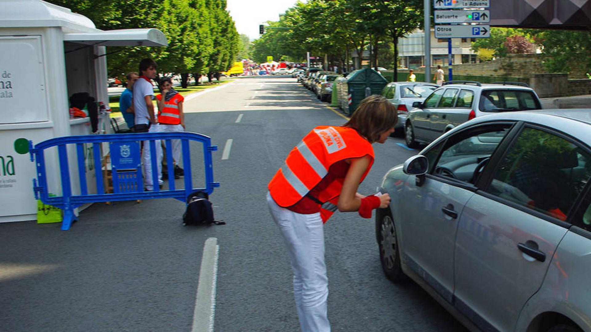 Una joven 'naranjito' da indicaciones a un conductor durante las fiestas de San Fermín de 2010.