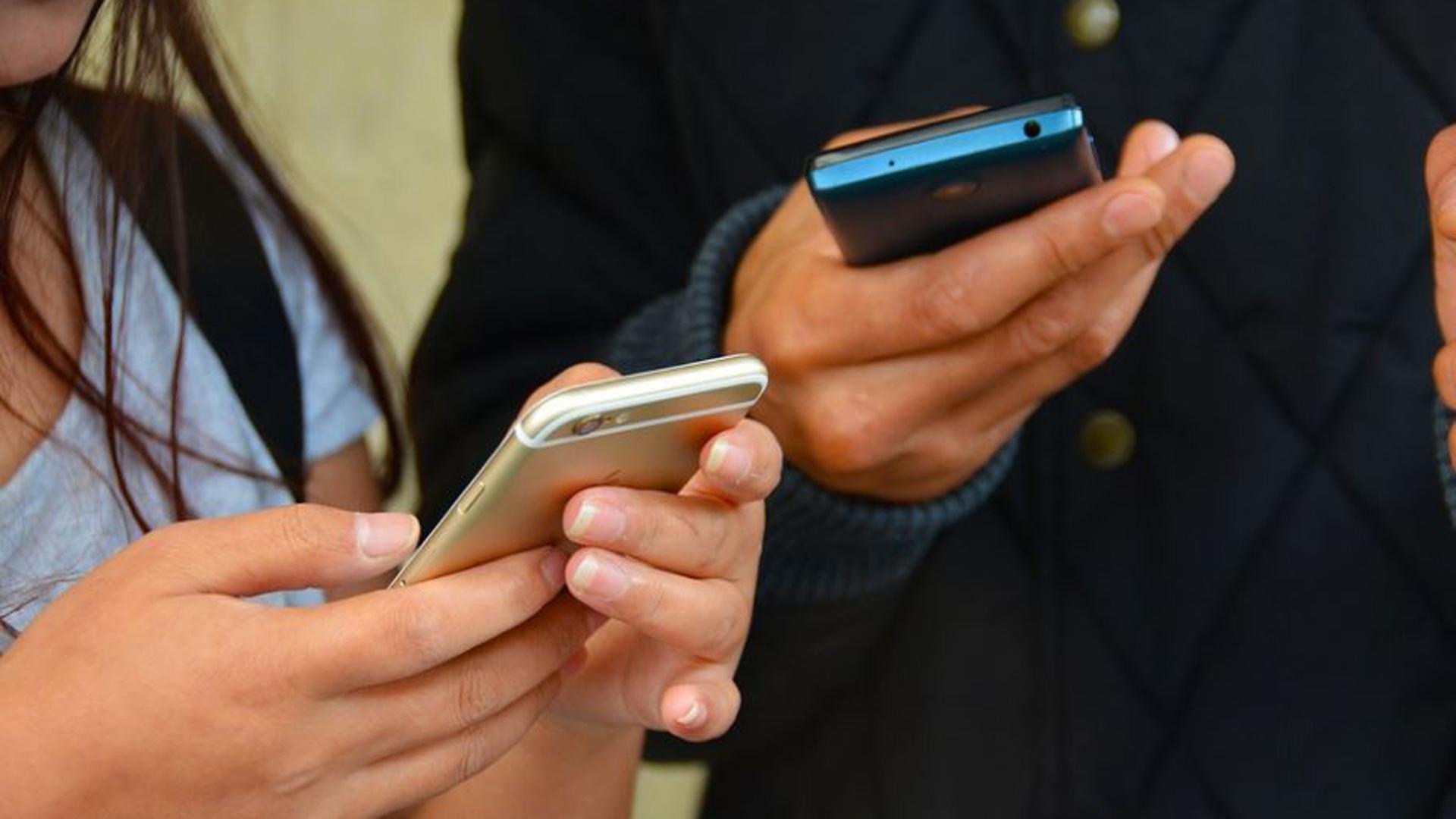 Dos personas consultan sus teléfonos móviles