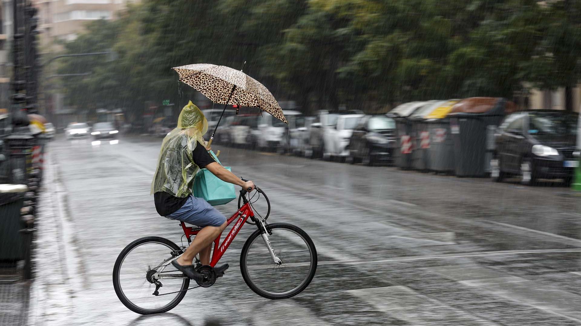 Un hombre circula en bicicleta bajo la lluvia en Valencia