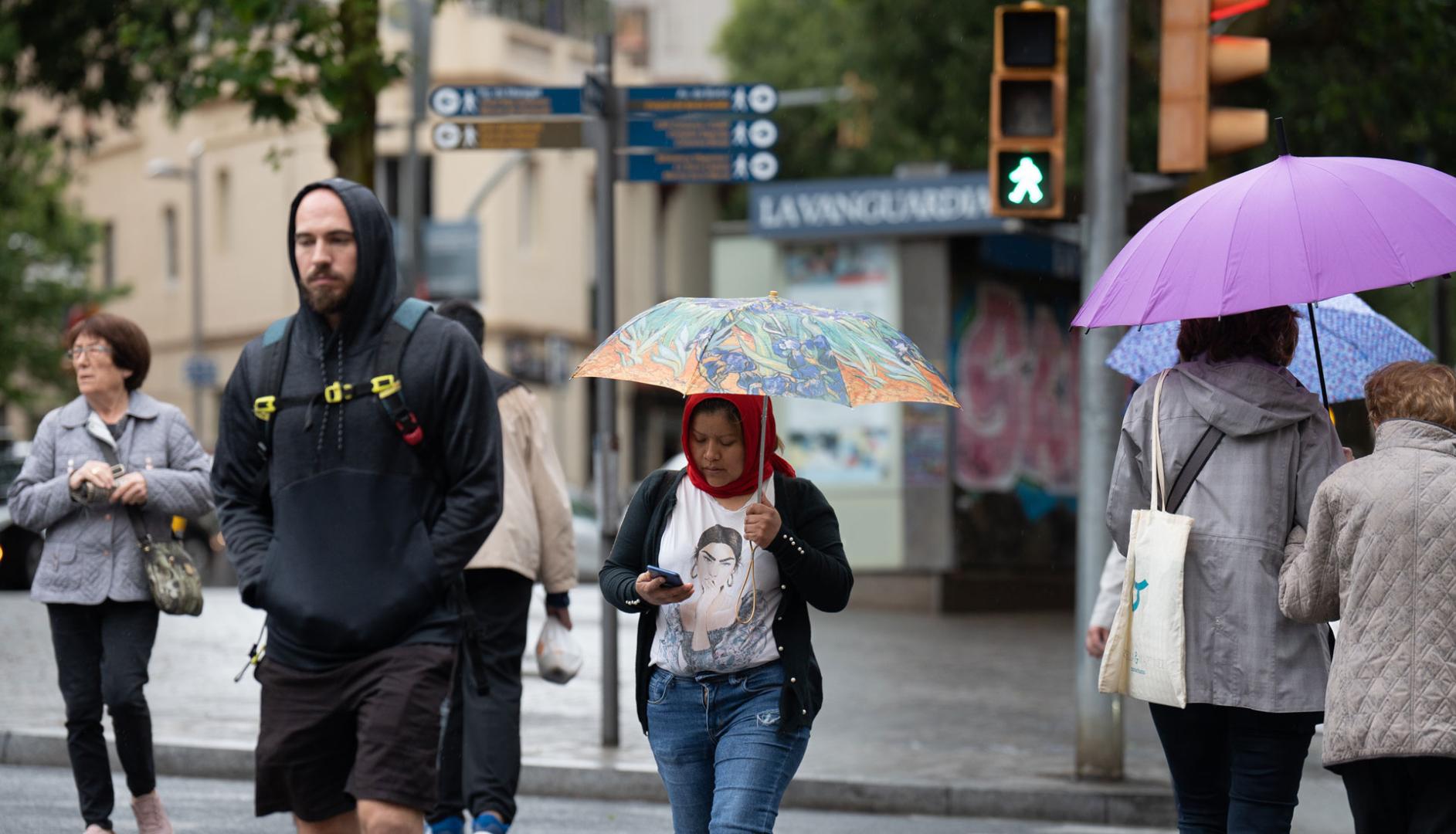 Varias personas con paraguas pasean por una de las calles de Barcelona bajo la lluvia