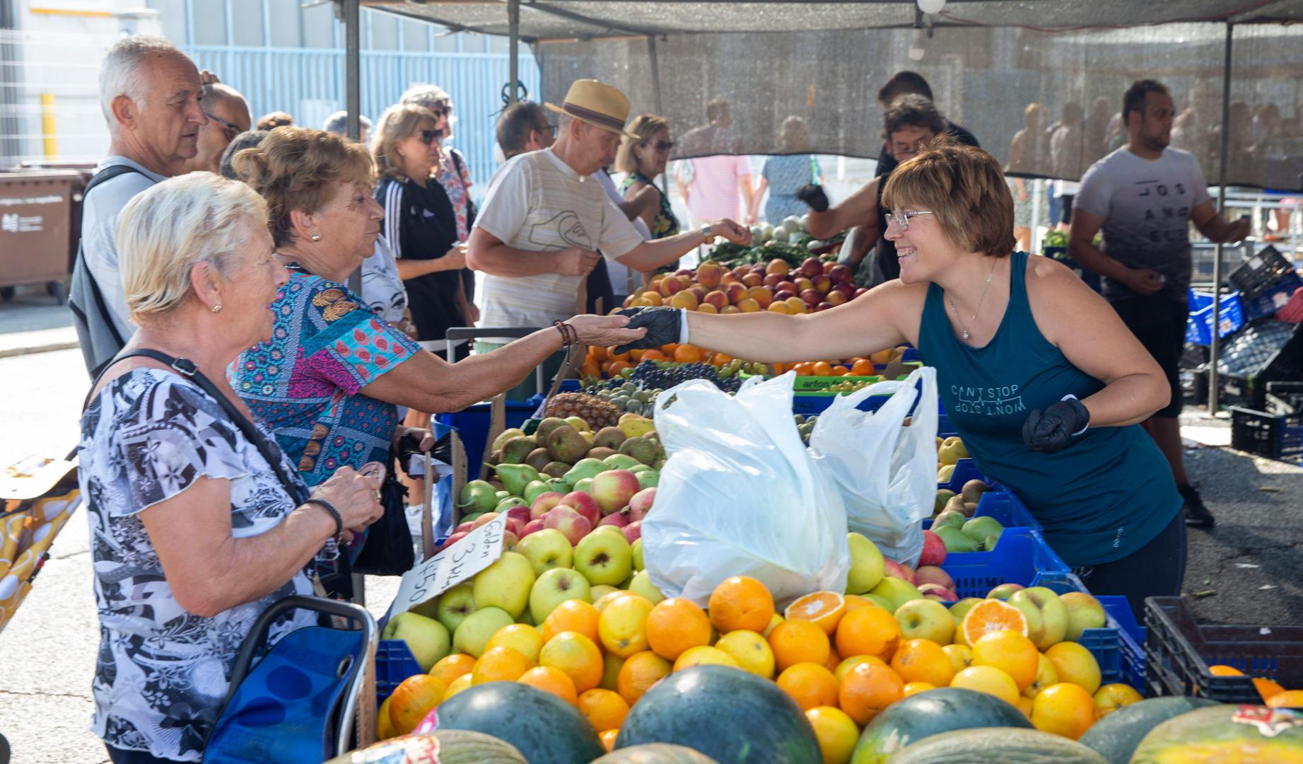 Varias personas compran en uno de los puestos de fruta y verdura del mercadillo de Landaben