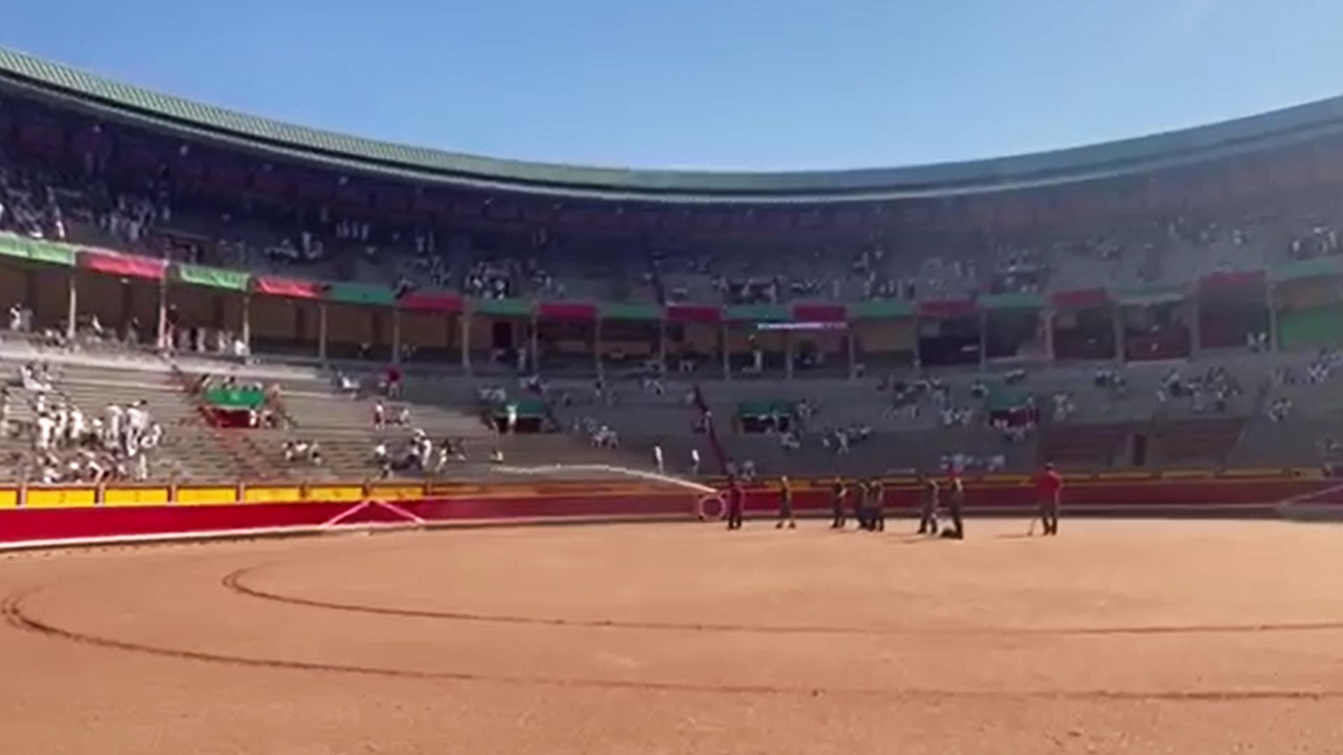 Los areneros riegan la arena de la plaza de toros antes de la corrida del 9 de julio