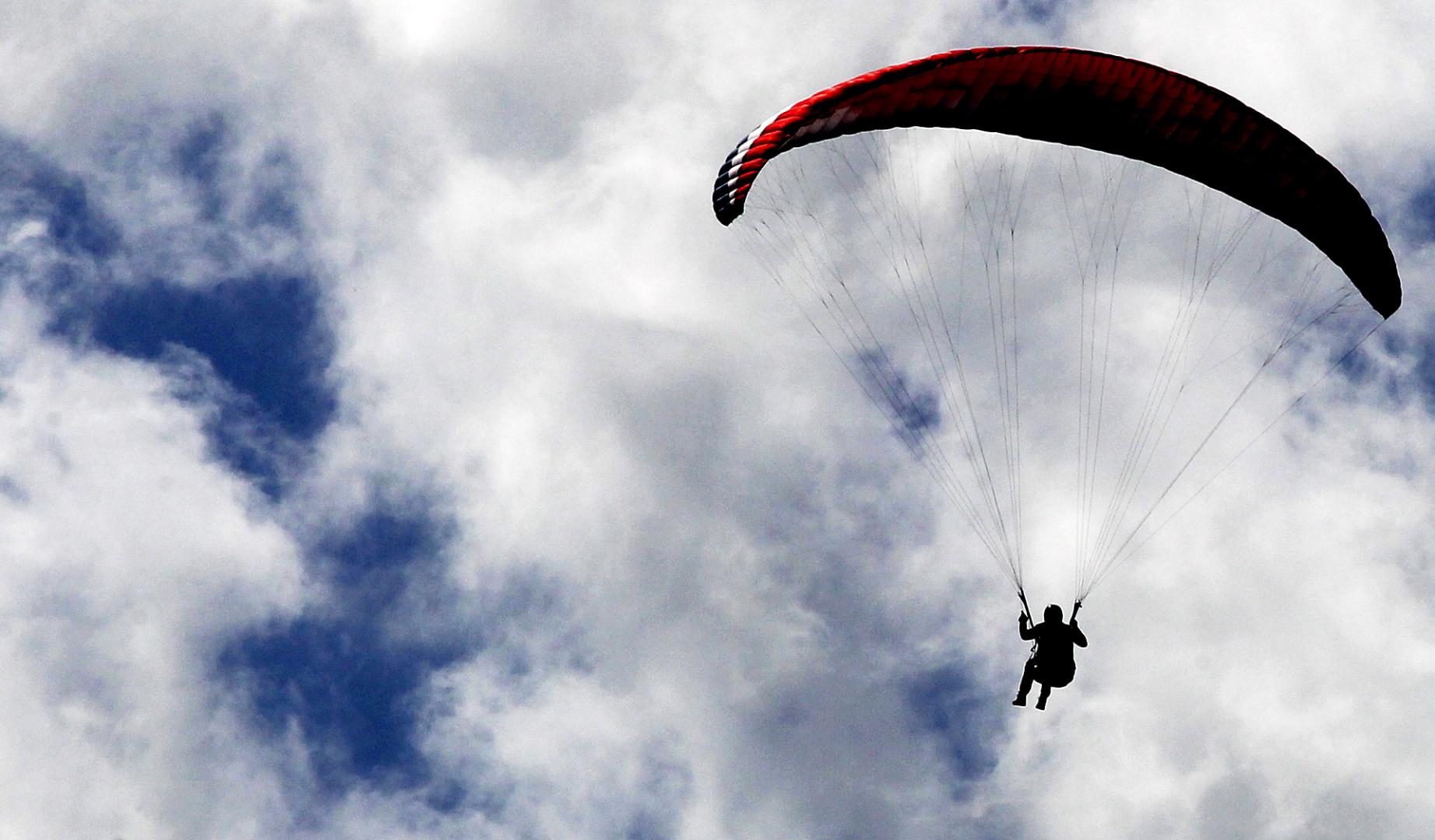Un practicante de parapente se abalanza sobre un mar de nubes bajas