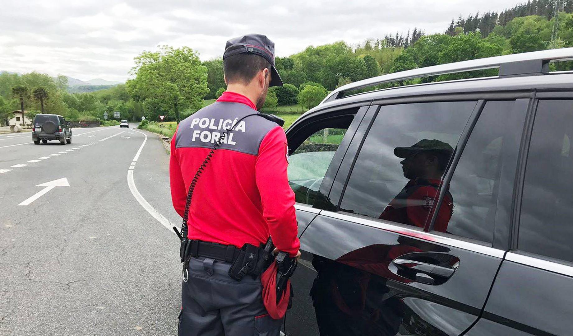 Un agente de la Policía Foral charla con el conductor de un coche, detenido en el arcén