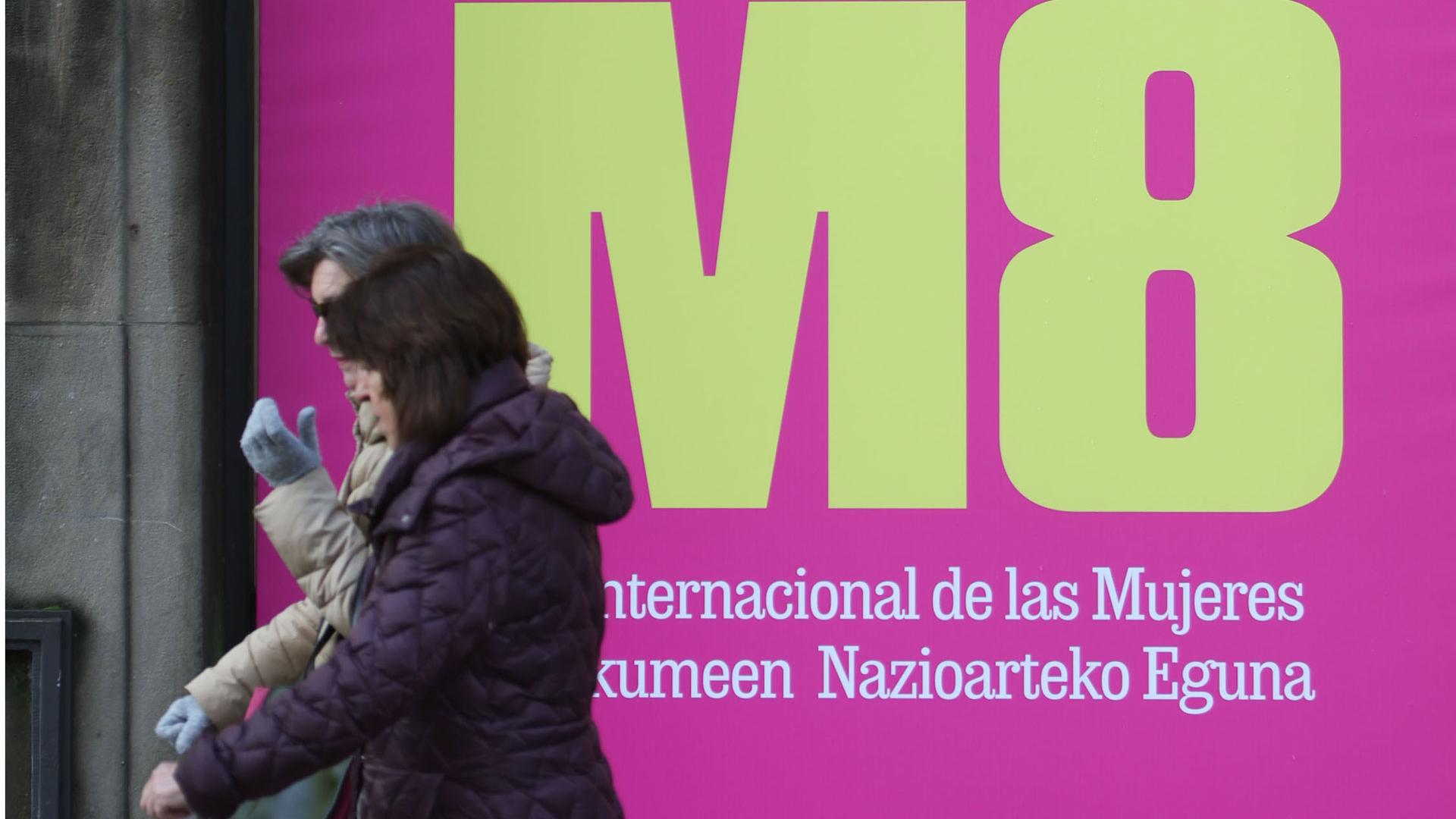 Dos personas pasan por delante de un cartel de la campaña lanzada con motivo del Día Internacional de la Mujer, habitual entre las acciones de sensibilización del Gobierno de Navarra