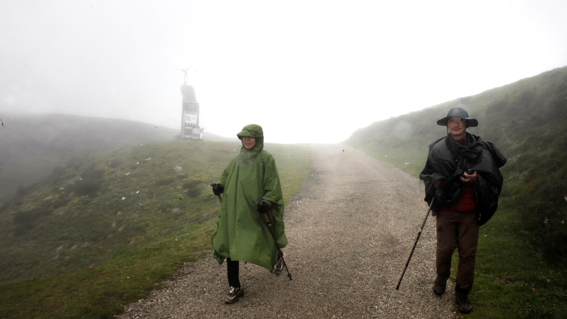 Alto de Lepoeder. 18 horas. Los peregrinos chinos, Li Sun, 43 años, y Liu Xue, 42, se abren paso  entre la niebla y el viento.