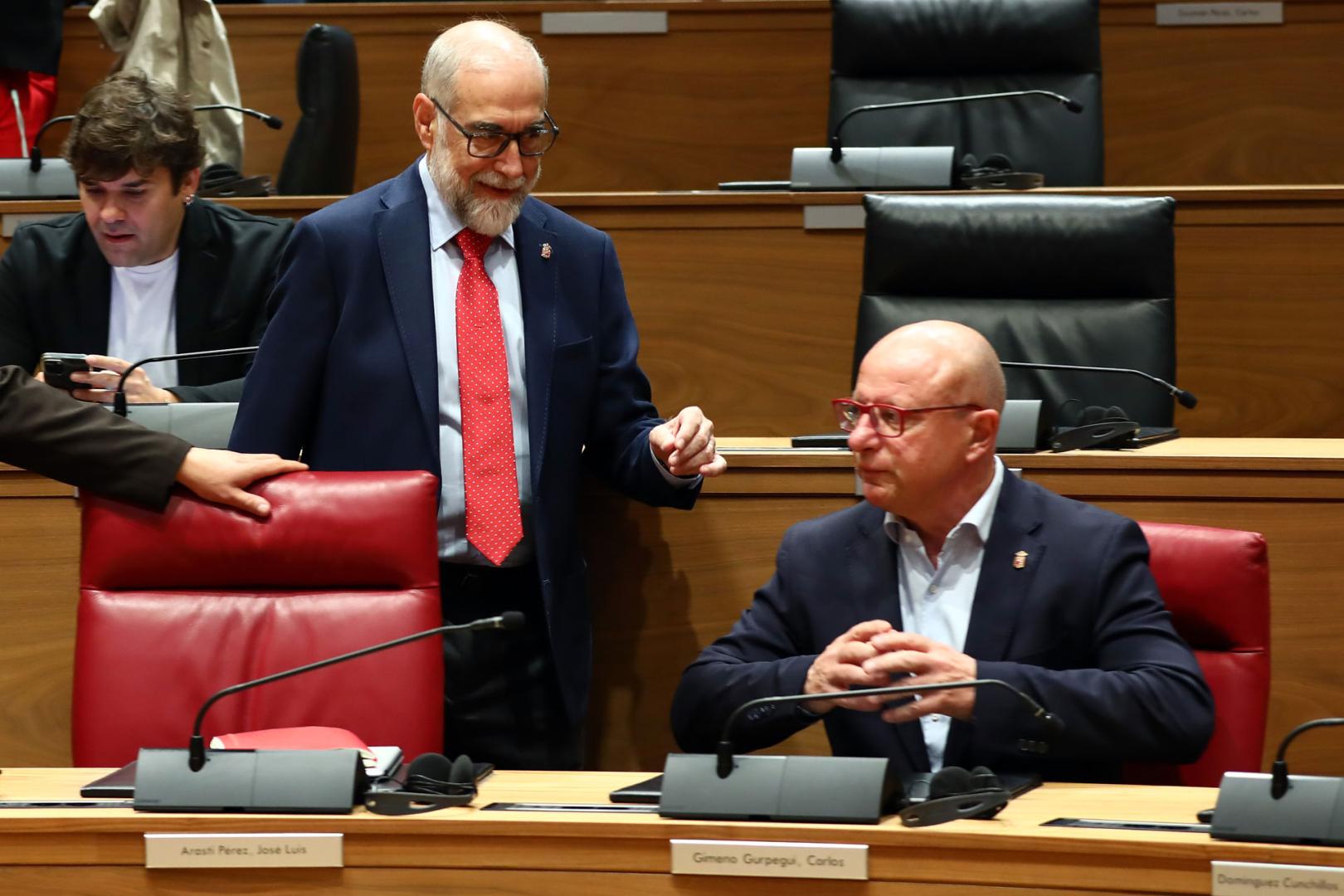 El consejero de Salud, Fernando Domínguez, conversa con el de Educación, Carlos Gimeno, en el pleno de este jueves