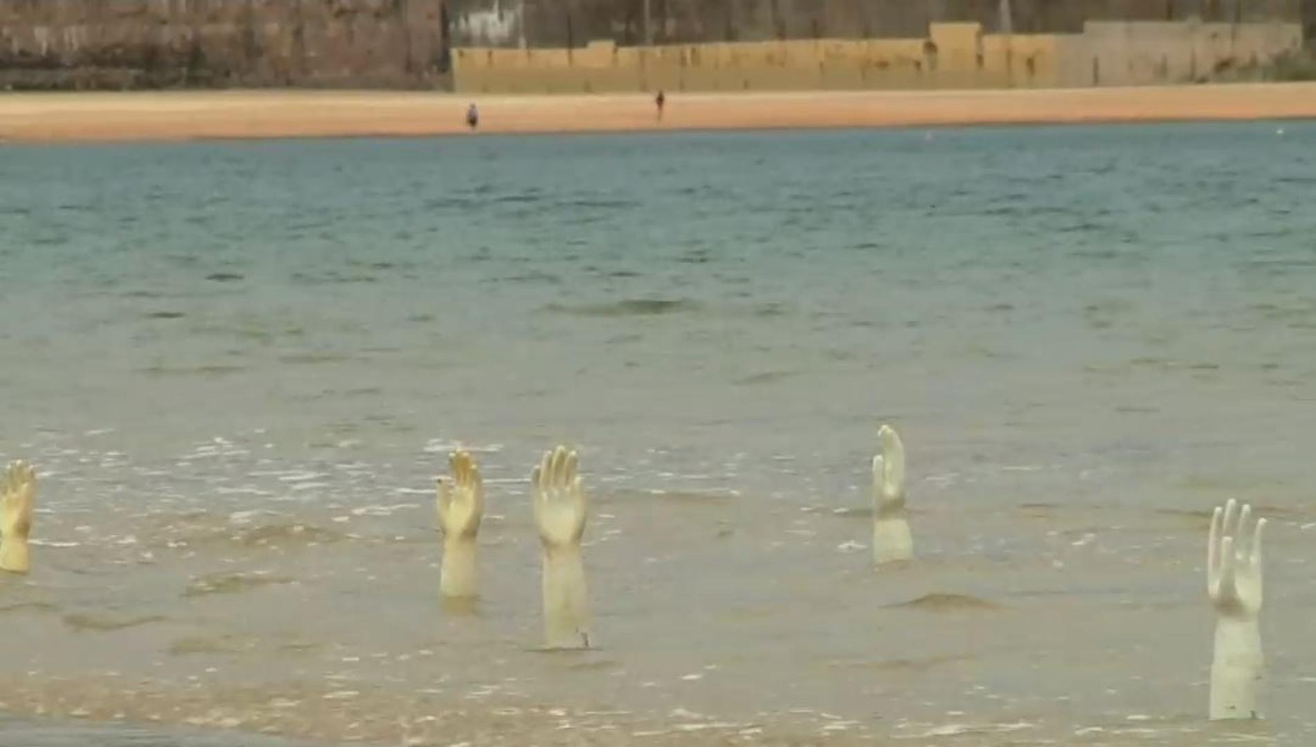 Vídeo de la colocación de la instalación 'EskuBideak',  con cientos de moldes de guantes en la playa de La Concha