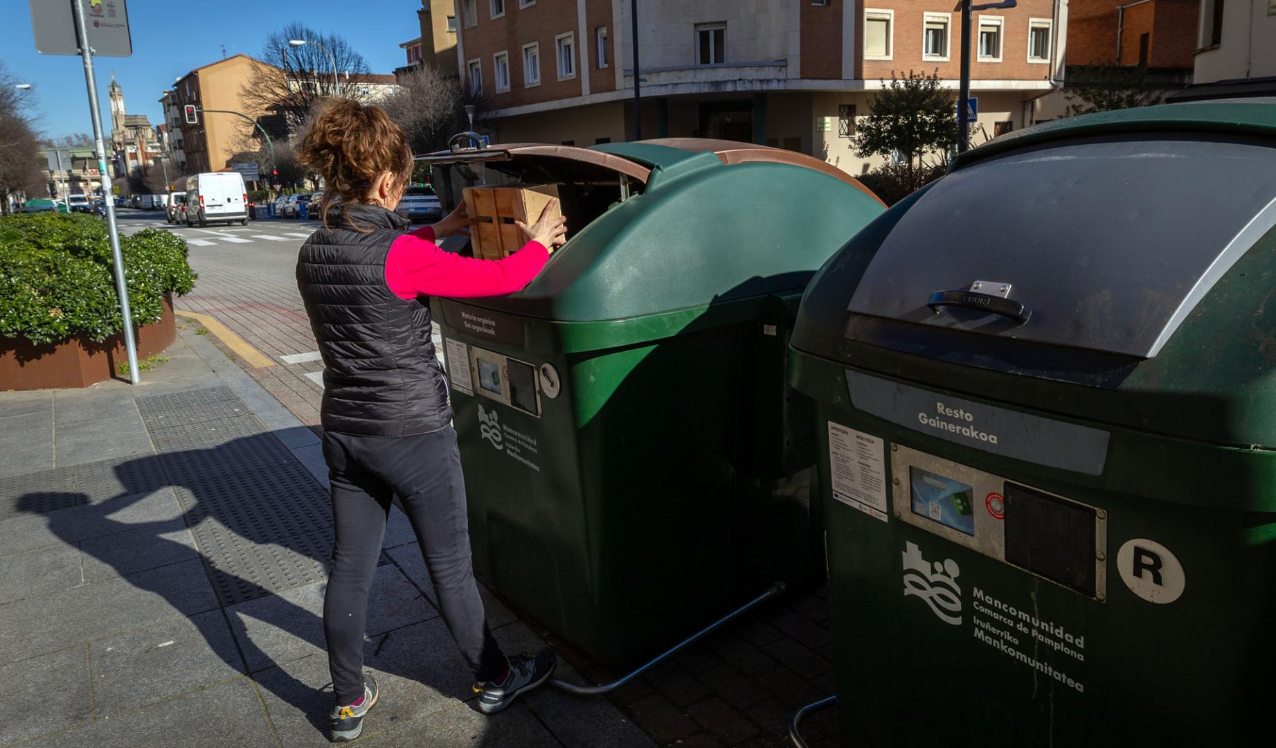 Una mujer deposita residuos en un contenedor de la calle Olite de Pamplona