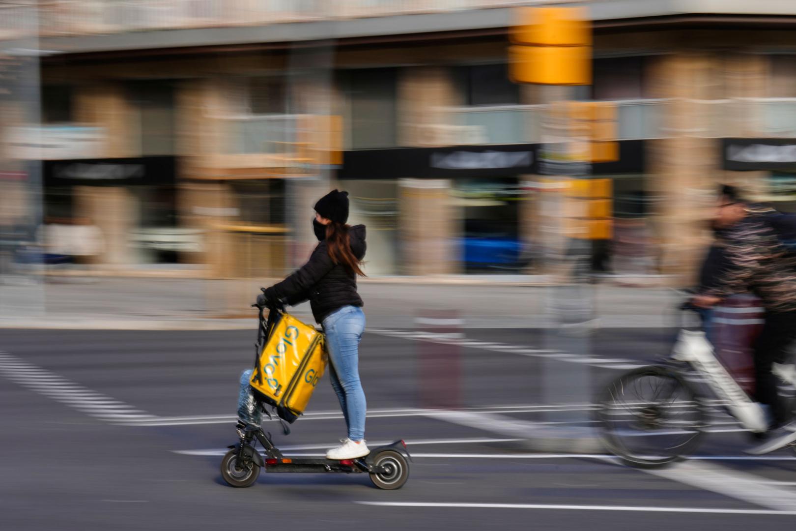 La conductora de un patinete eléctrico circula por una calle de Barcelona sin casco