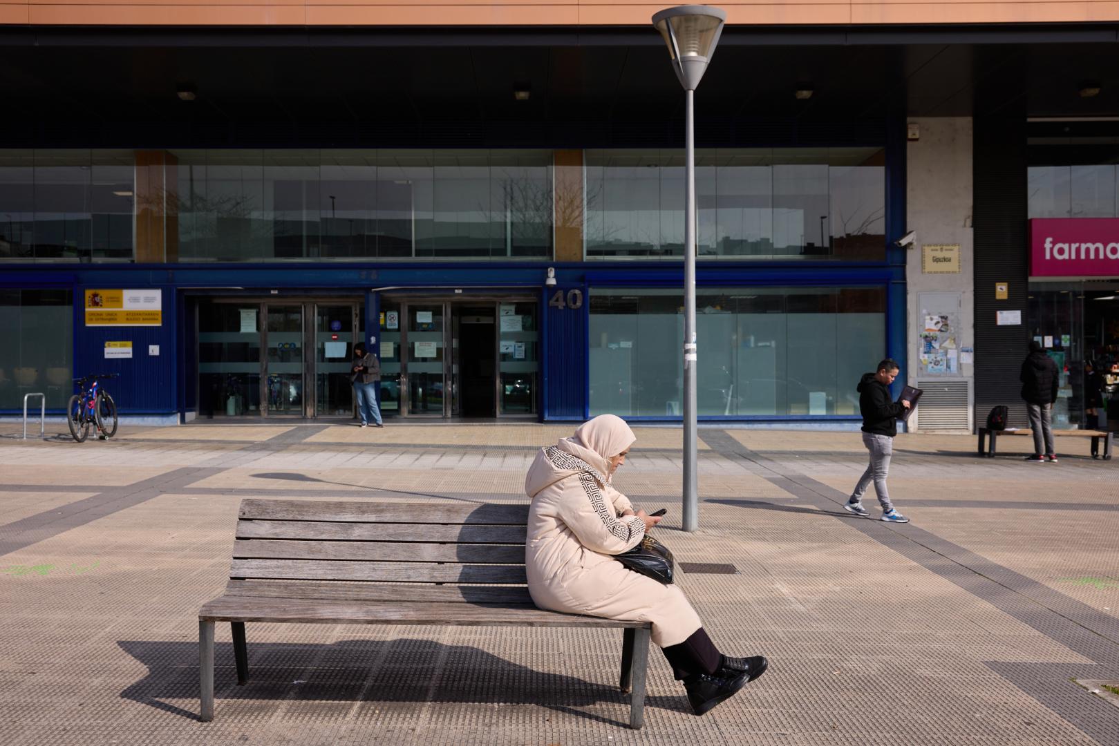 Una mujer consulta su móvil en las inmediaciones de la oficina de Extranjería de Pamplona