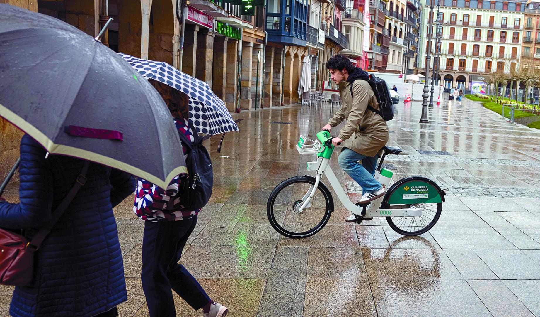 Un usuario del sistema de alquiler de bici eléctrica, ayer bajo la lluvia.