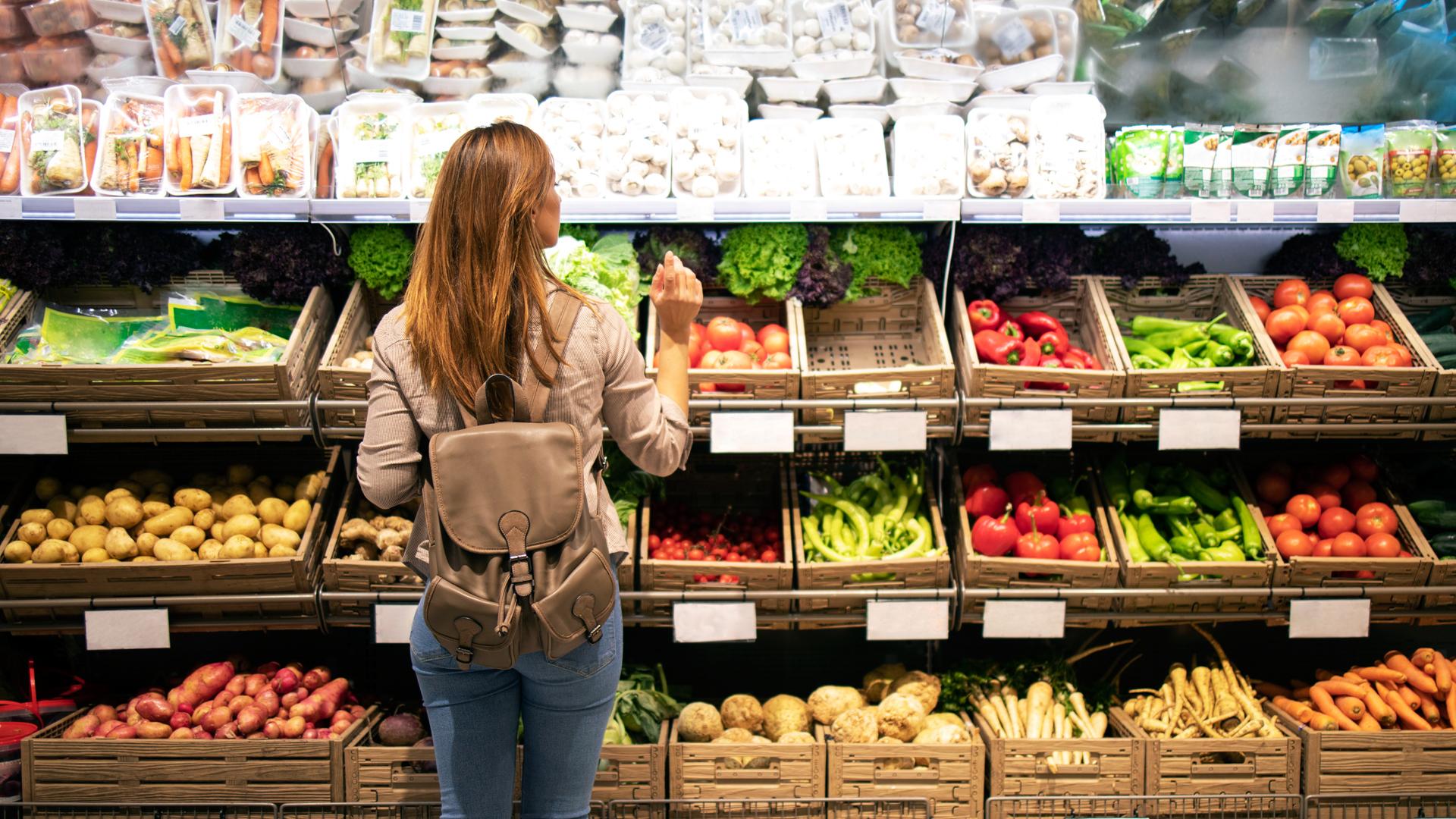 Una mujer, en la sección de verduras de un supermercado