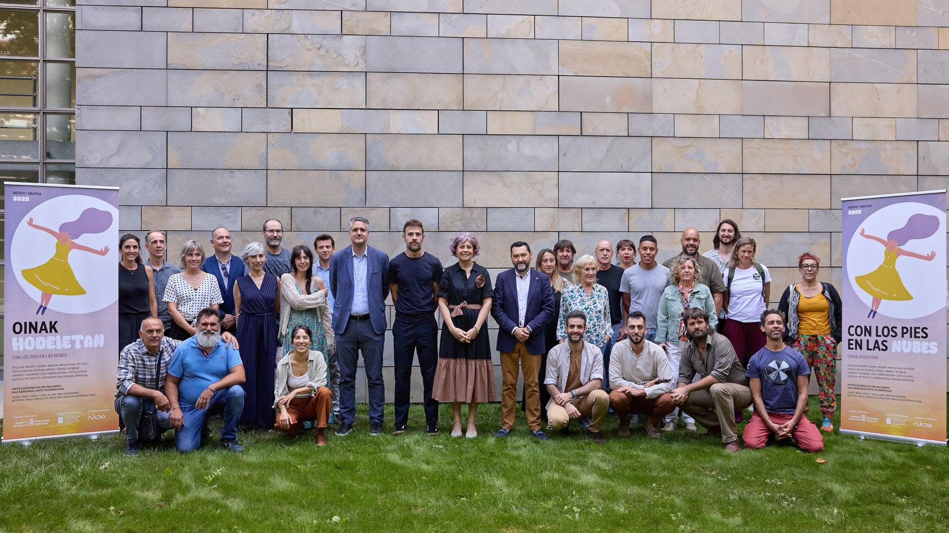 En el centro, de izquierda a derecha, Ignacio Apezteguía, director de Cultura (con chaqueta azul); Rubén Jauquicoa, de Fundación Baluarte; Rebeca Esnaola, consejera de Cultura, Deporte y Turismo; y Jesús María Rodríguez, director general de Administración Local y Despoblación del Departamento de Cohesión Territorial. El resto del grupo está compuesto por Maitena Muruzábal, coordinadora del programa; representantes de algunas de las localidades en las que tienen lugar espectáculos de esta edición; miembros de la compañía De Improviso, que actuó durante la presentación; y artistas y miembros de otras compañías participantes en esta edición de Con los pies en las nubes