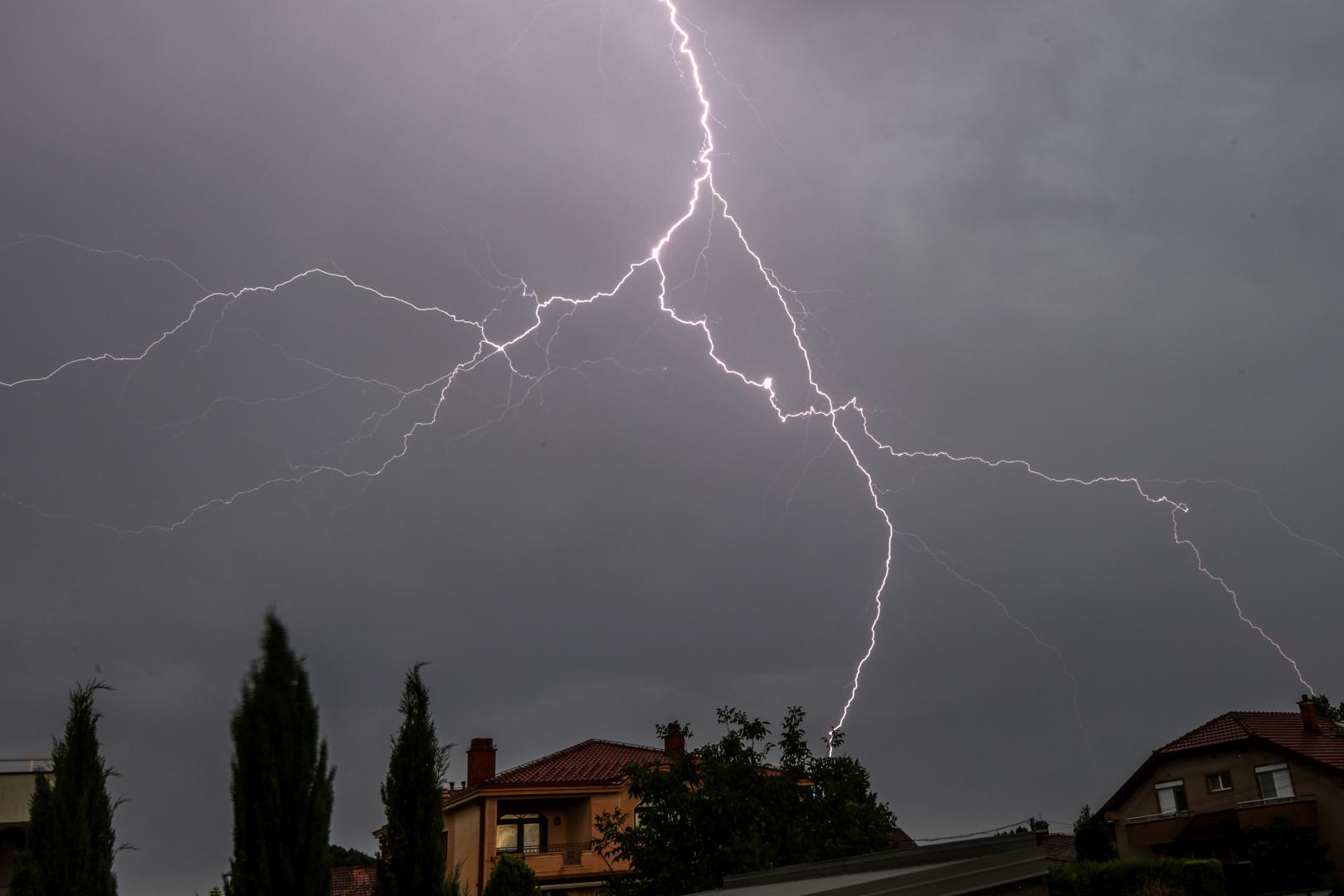 Un rayo que cae cerca de unas casas en una tormenta eléctrica