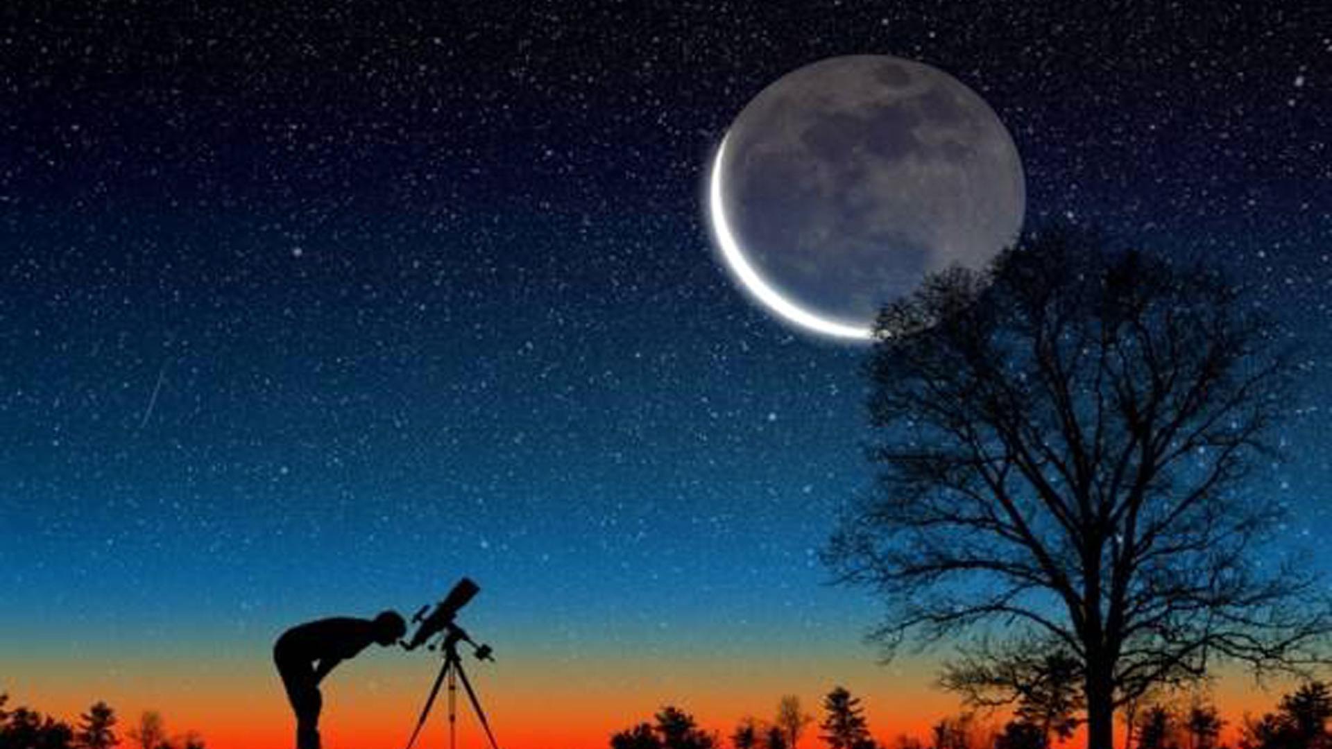 Una persona observa la luna con ayuda de un telescopio