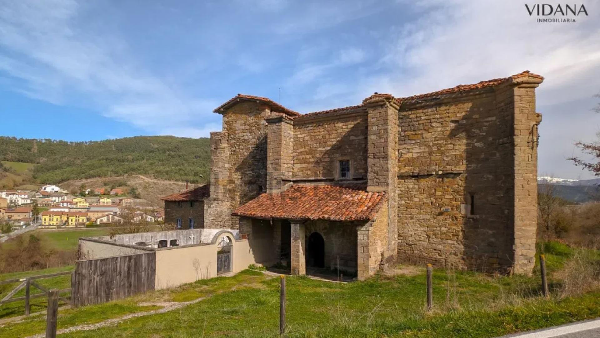 Fachada con la puerta de entrada a la iglesia y el pequeño cementerio colindante