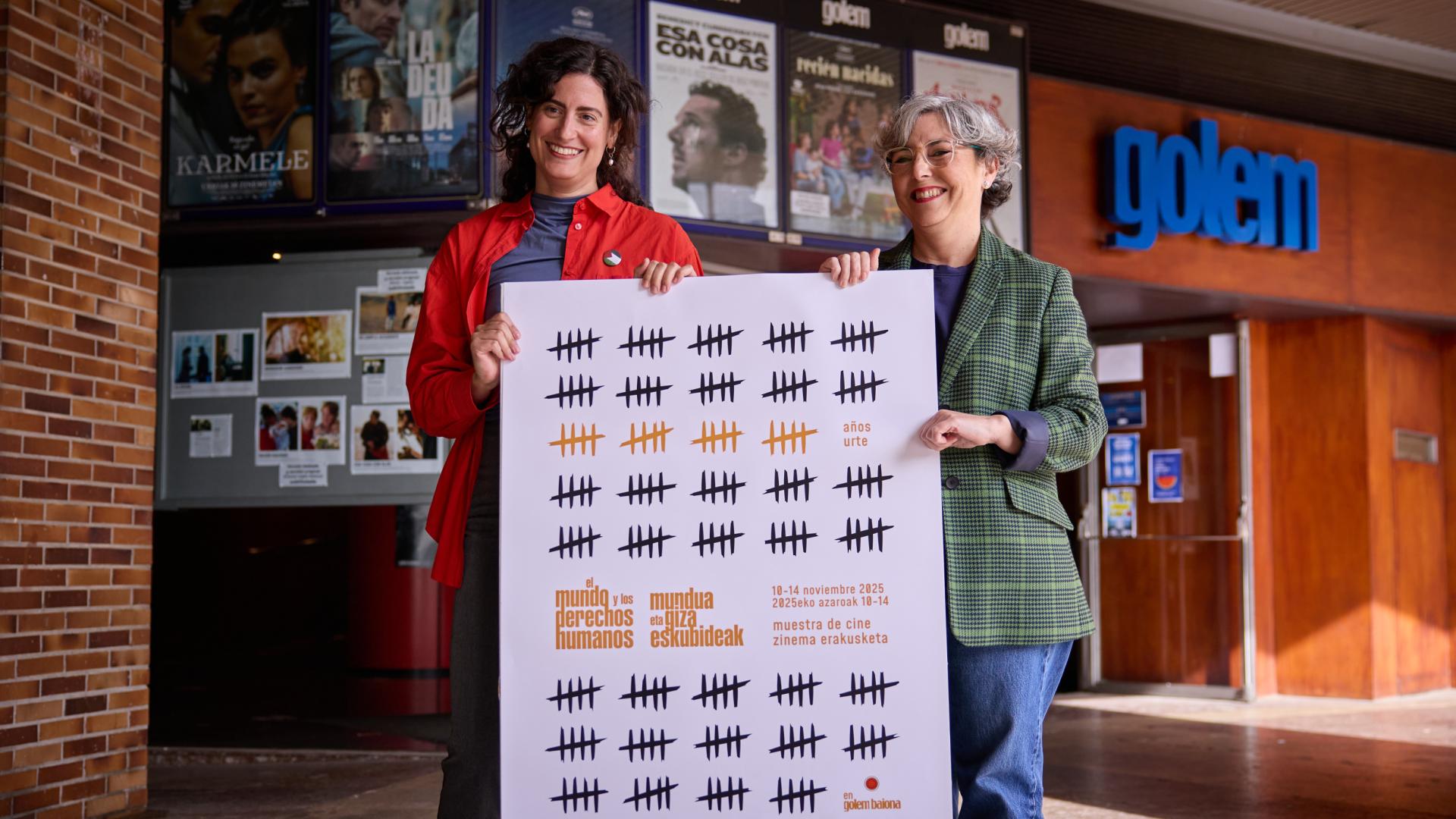 Lara Molina y Begoña Arrondo con el cartel de la XX edición de El mundo y los derechos humanos
