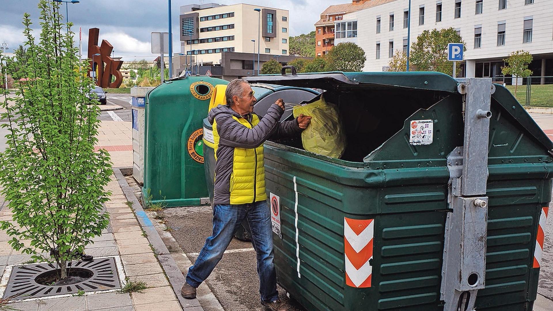 Un hombre deposita basura en un contenedor de Tafalla