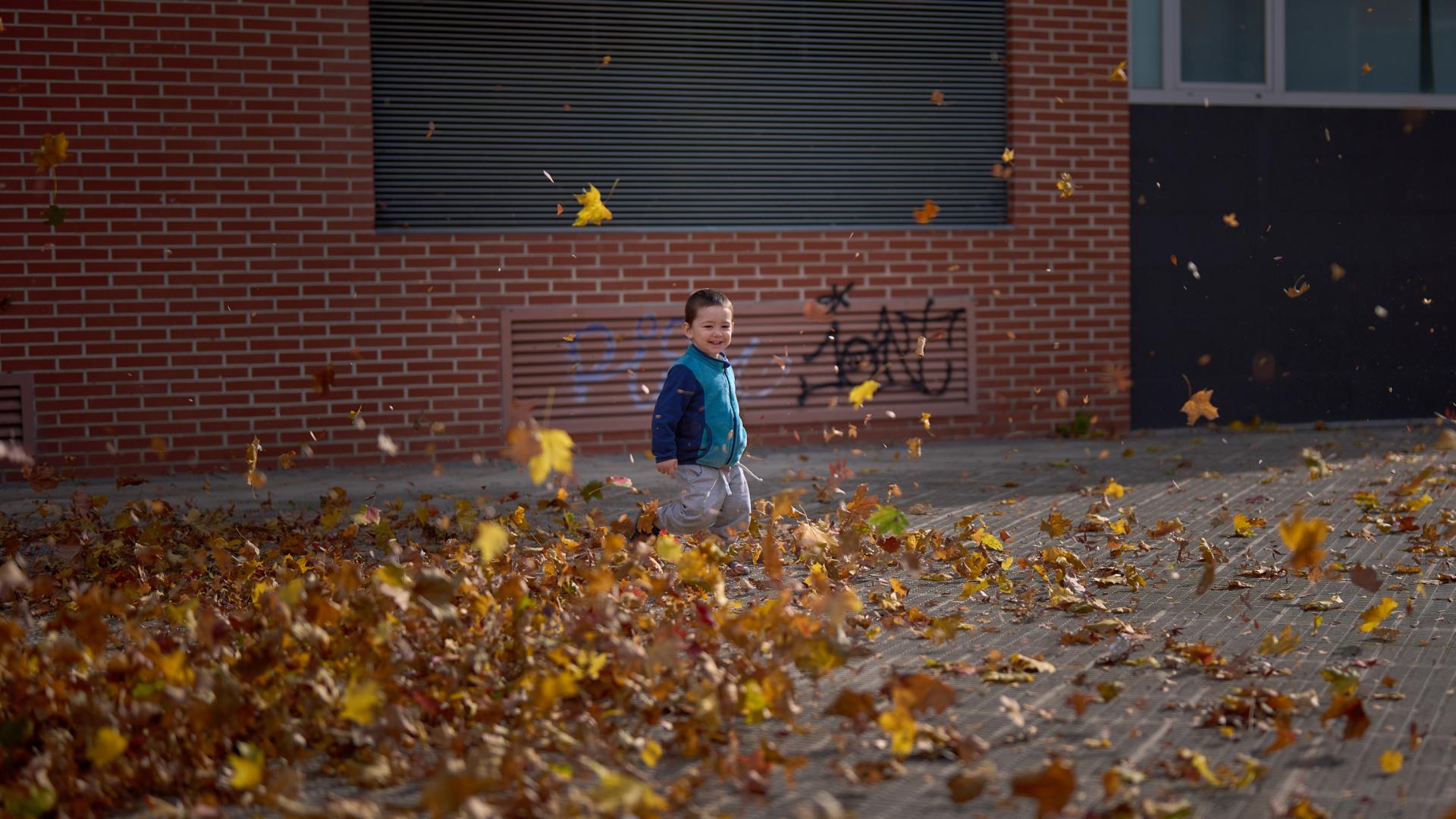 Un niño juega con hojas en Pamplona, una mañana de este otoño.