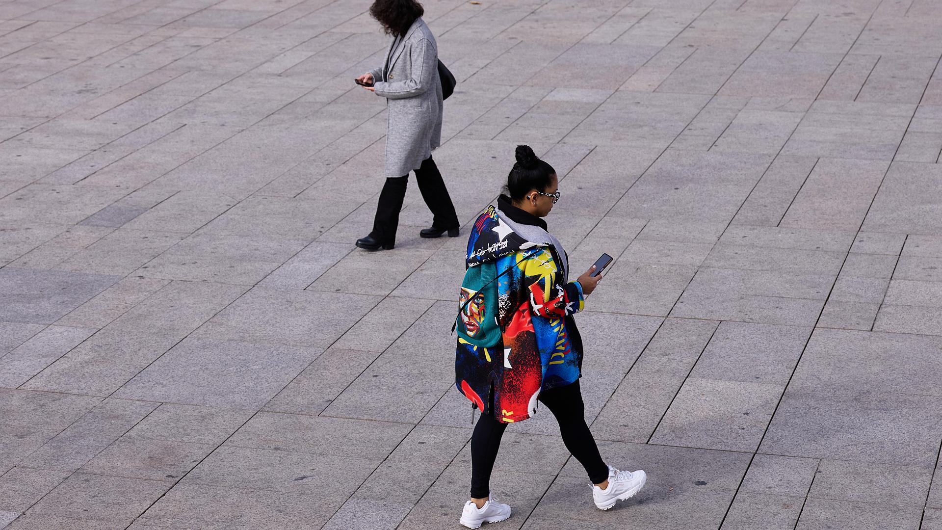 Dos mujeres observan su móvil mientras caminan por la Plaza del Castillo /
