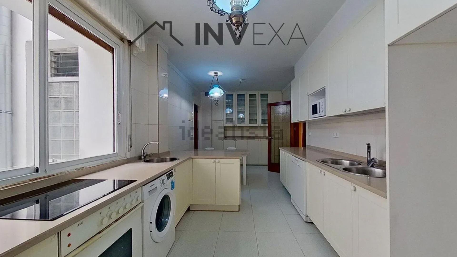 Cocina con mobiliario a ambos lados y ventana a uno de los patios