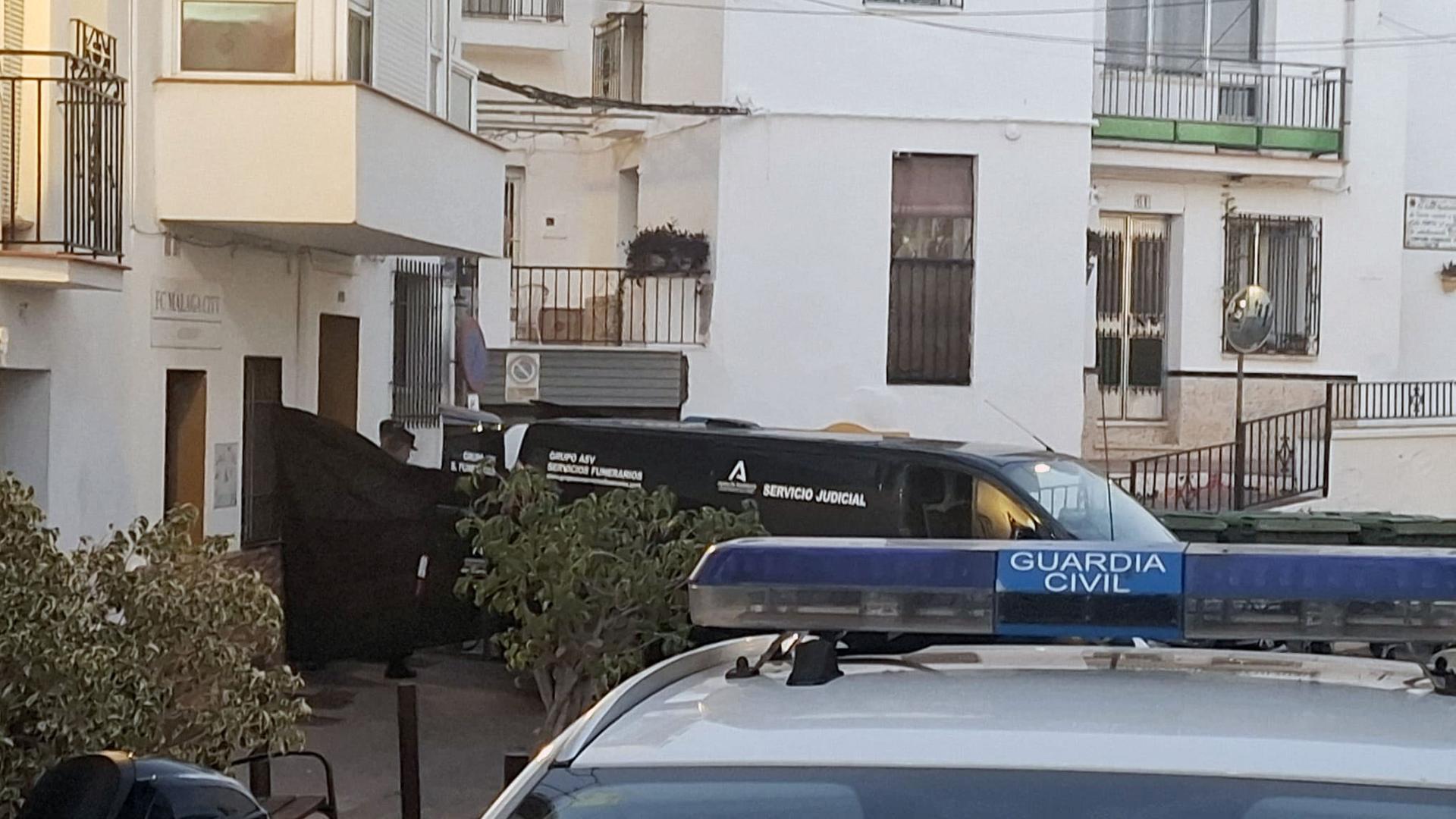 Coches de la Guardia Civil y de los servicios funerarios, junto a la vivienda en Torrox donde este martes han fallecido cuatro personas de una misma familia por inhalación de gas