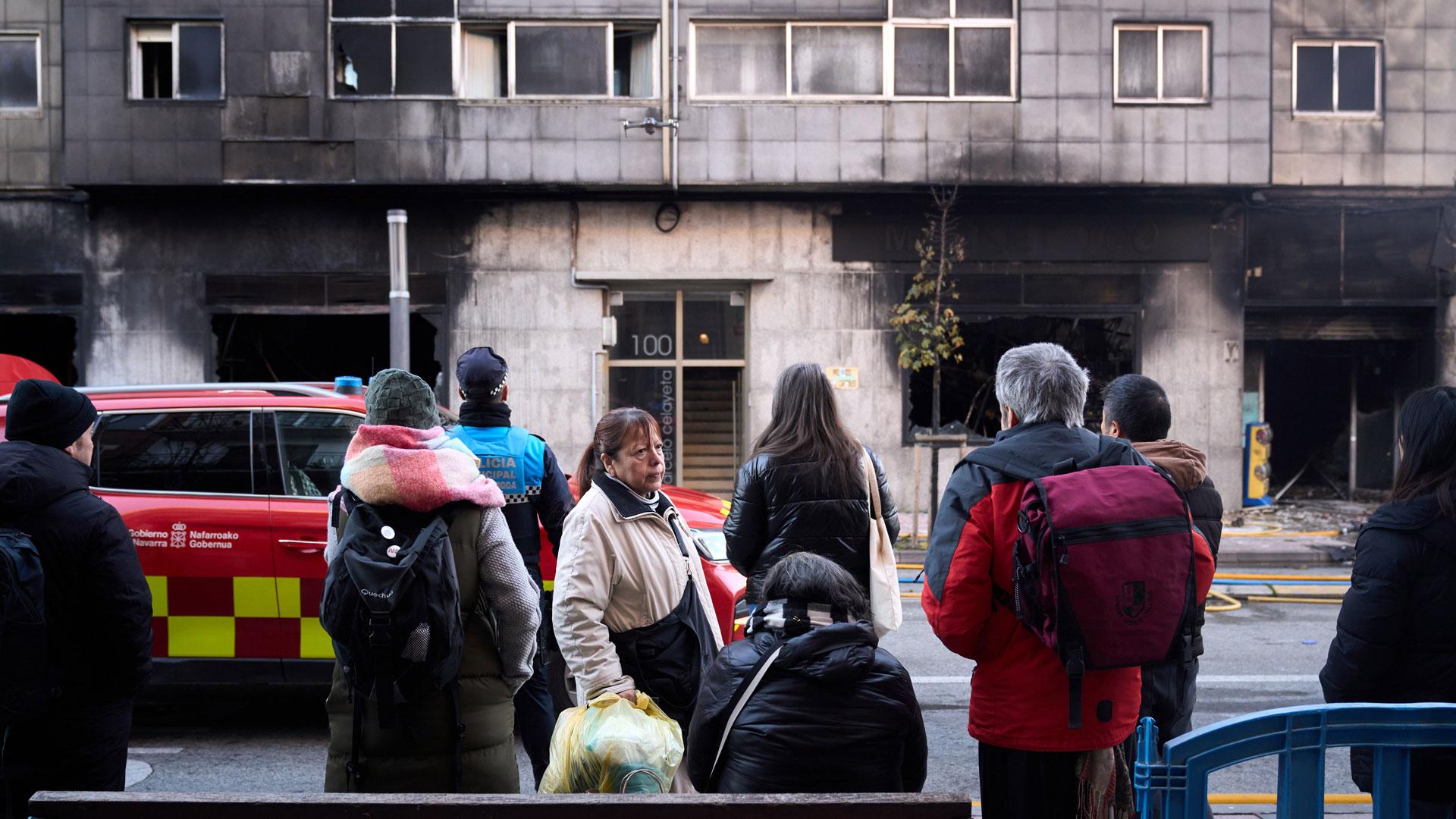Vecinos y curiosos observan los efectos del fuego en el edificio tras el incendio de un bazar en la Rochapea