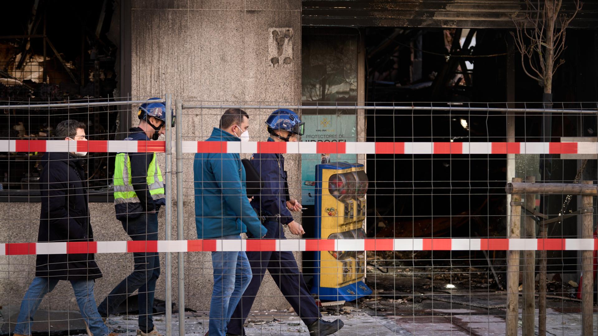 Agentes de la Policía Nacional, que investigarán lo ocurrido, ayer junto a los restos del bazar incendiado