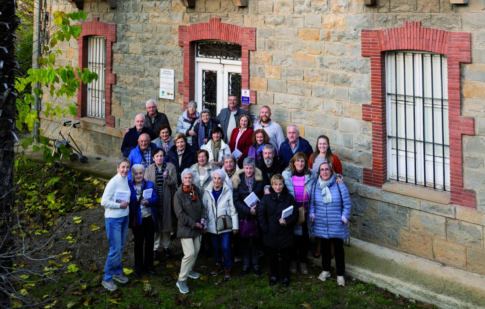 Presentación del libro en el instituto La Granja, con presencia de familiares y antiguos empleados de las granjas experimentales de Pamplona. Ante el cartel que recuerda el pasado del centro.