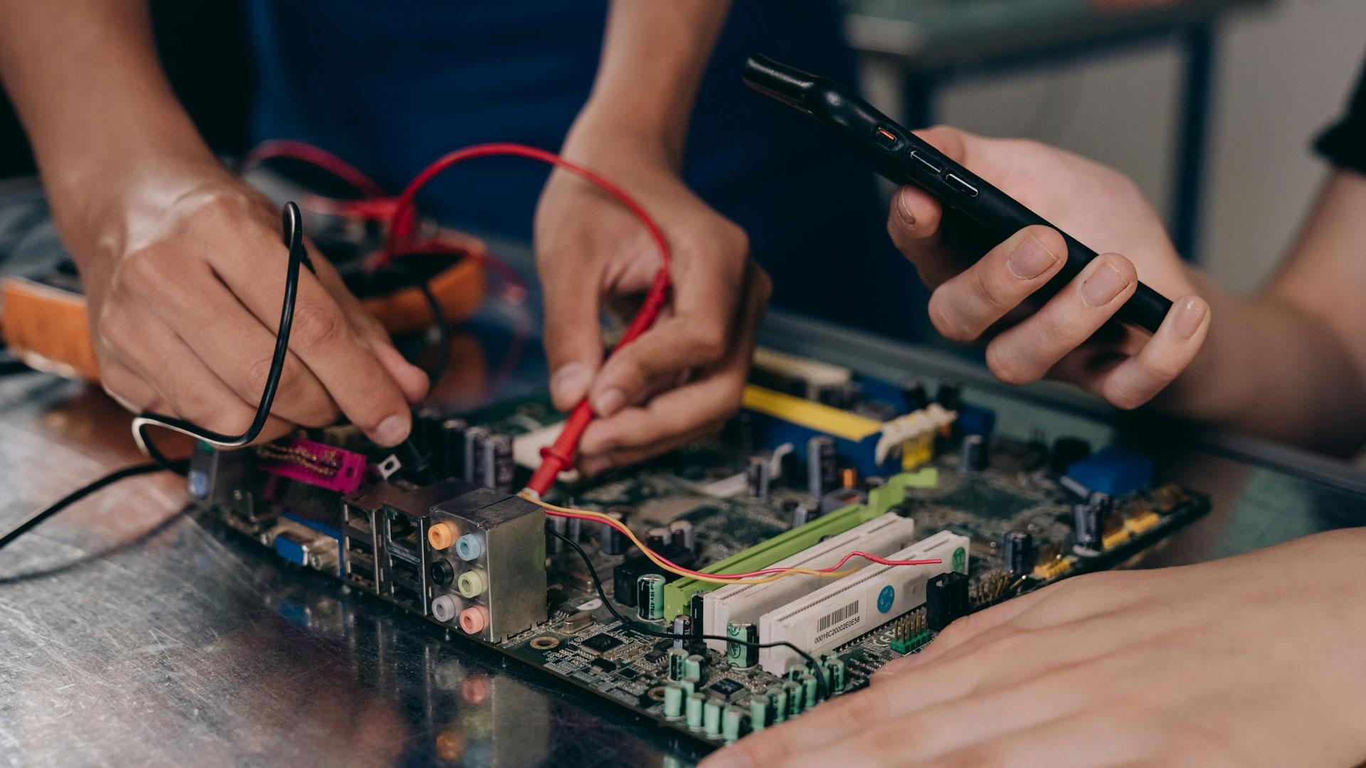 Dos personas trabajando en una placa electrónica