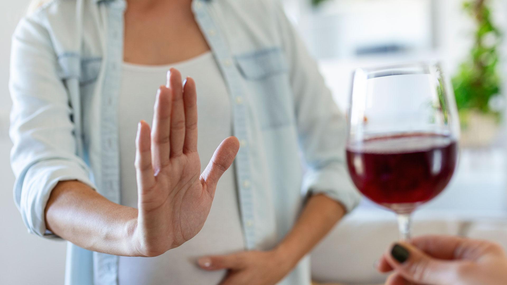 Una mujer rechaza una copa de vino