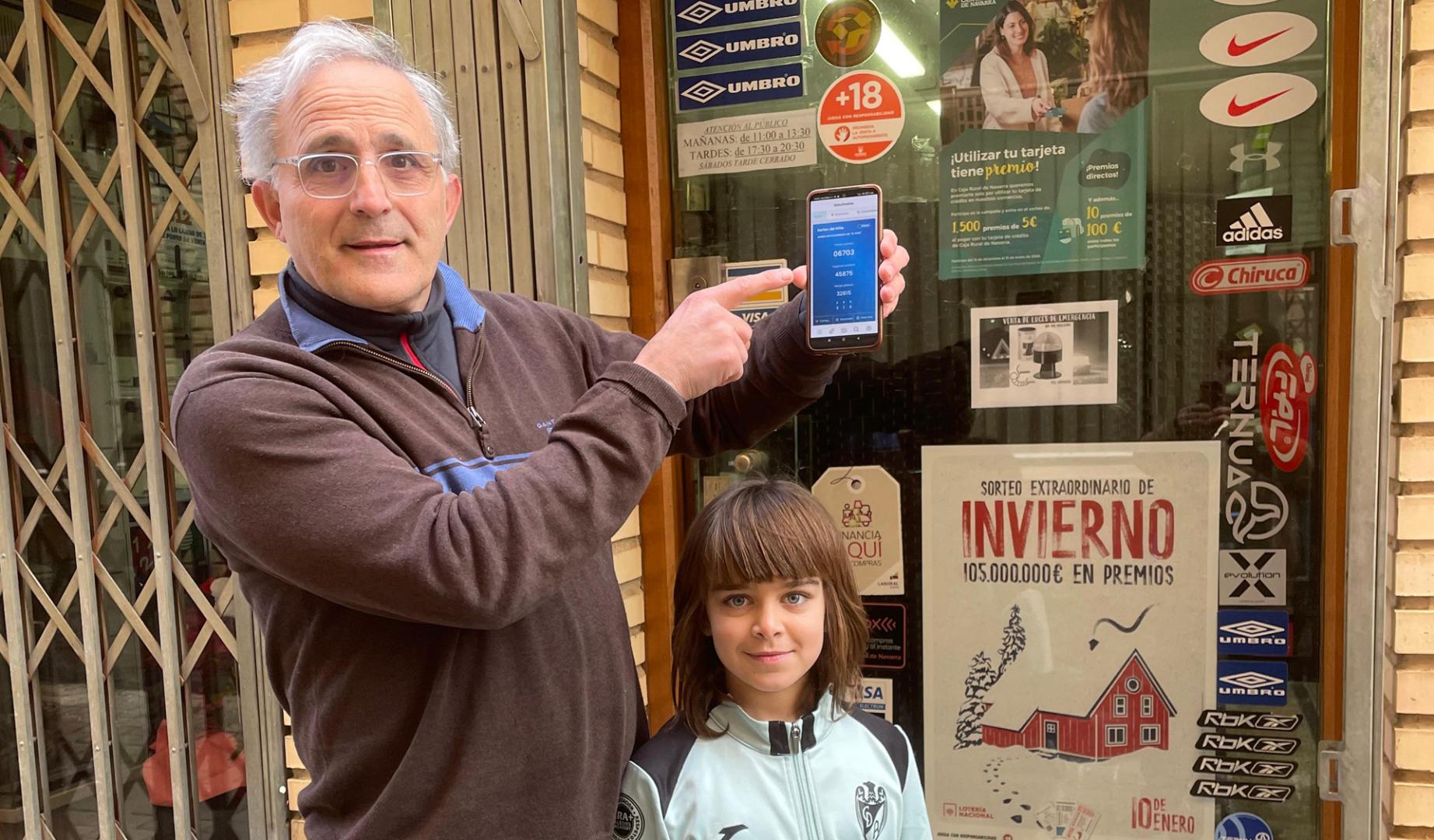 El dueño delante de la tienda deportes donde expendio de máquina el décimo premiado con el gordondel Niño , Serafín García Segura y su sobrina Vega García Sainz